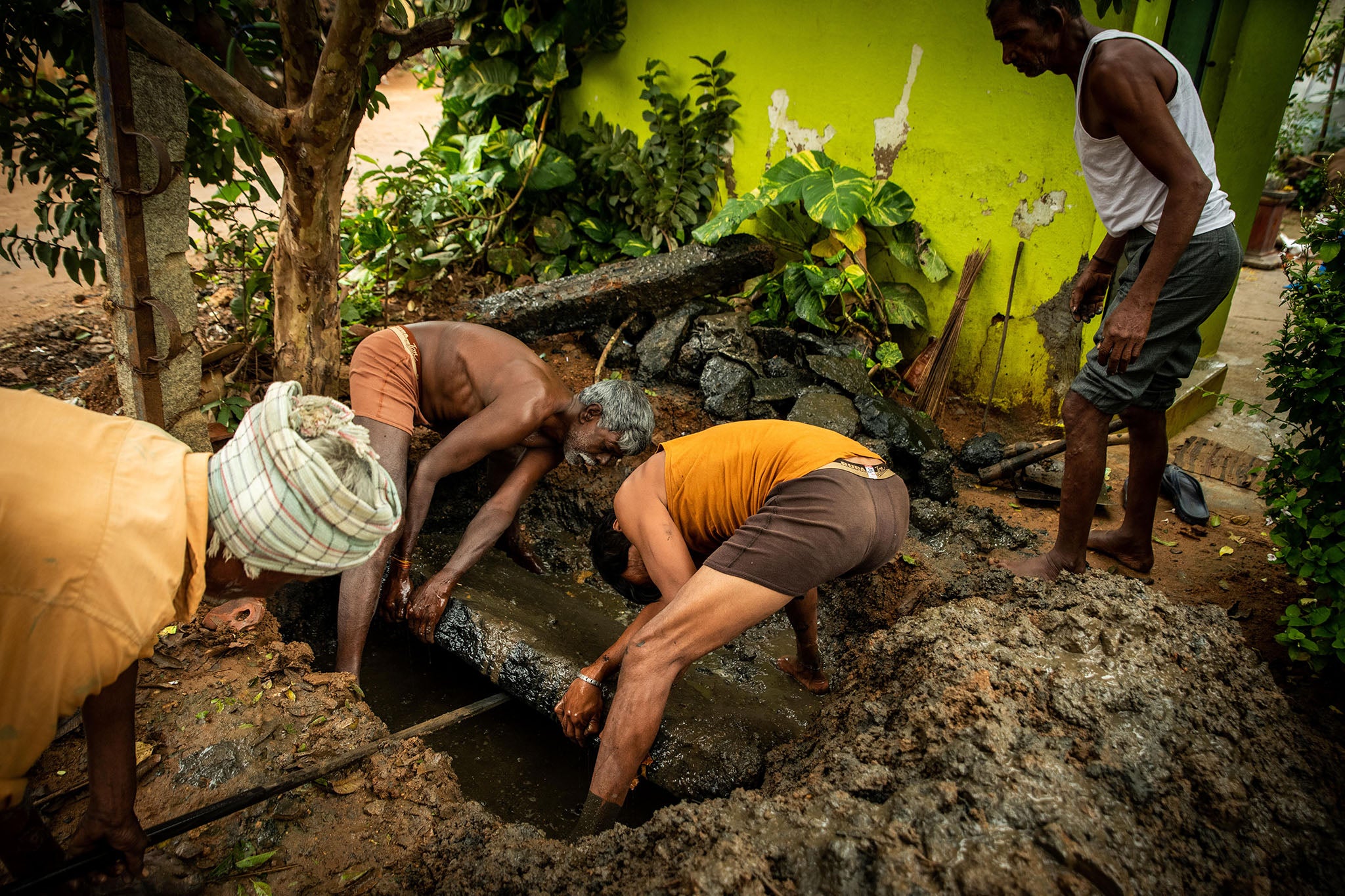 Workers open a sewage pit behind a home in Bangalore