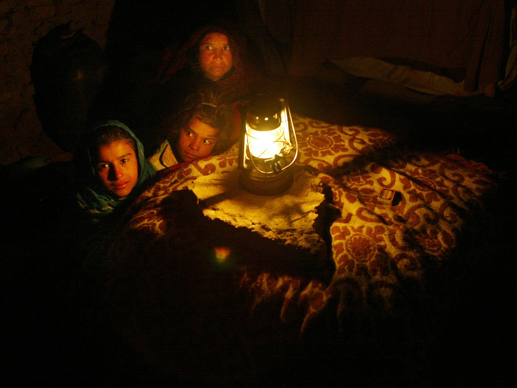 Families sit round blanketed tables with hot coals underneath them