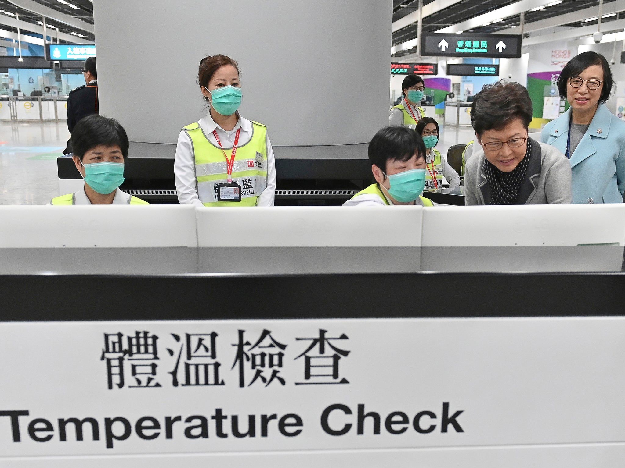 Carrie Lam stands at a temperature check booth