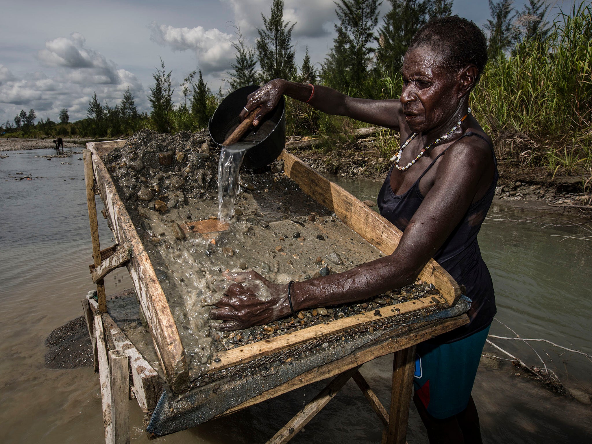 An illegal gold miner sifts through sand and rock as they pan for gold