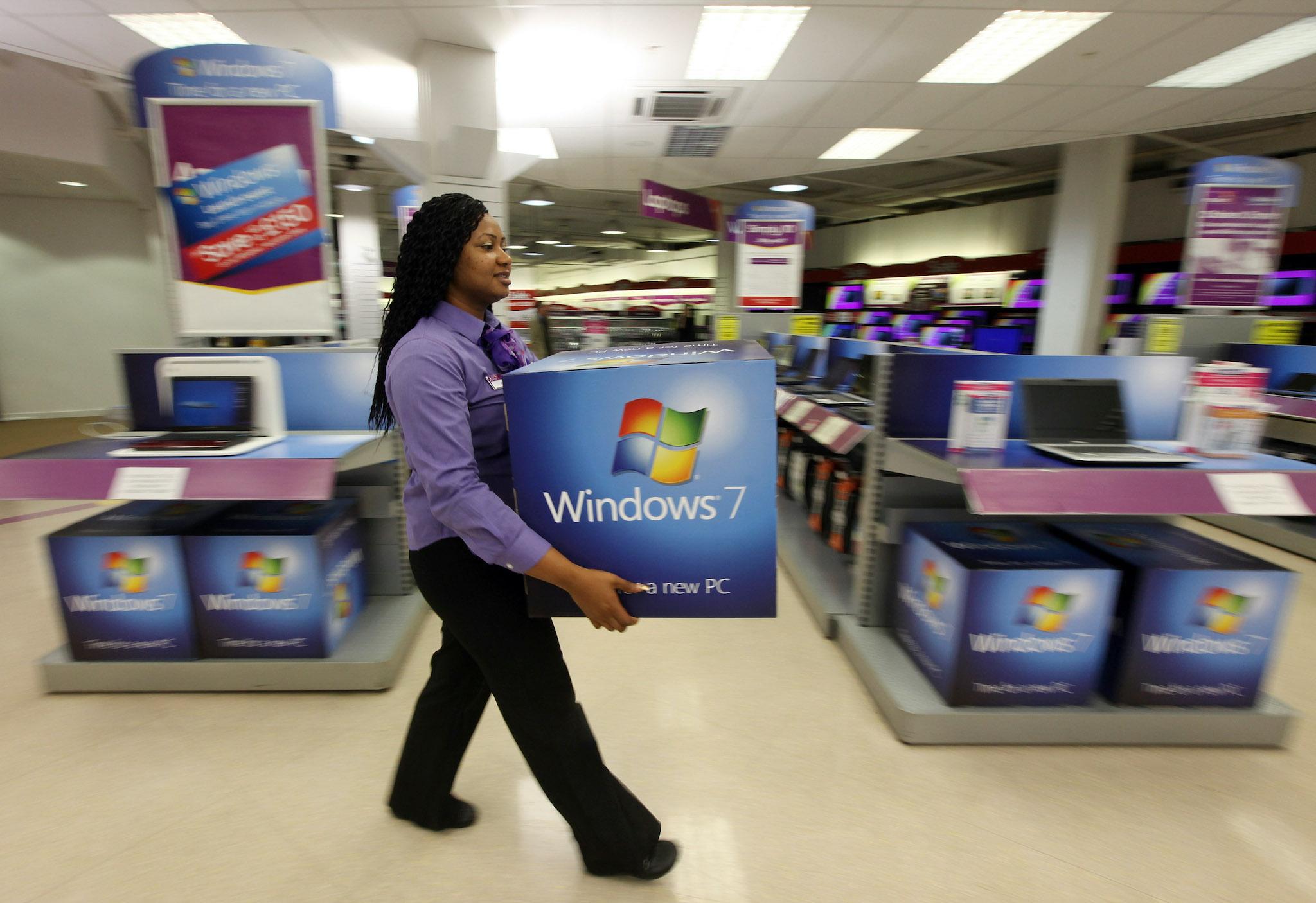 A computer store employee carries promotional signage for Microsoft's new operating system 'Windows 7' ahead of its official launch at midnight tonight on October 21, 2009 in London, England