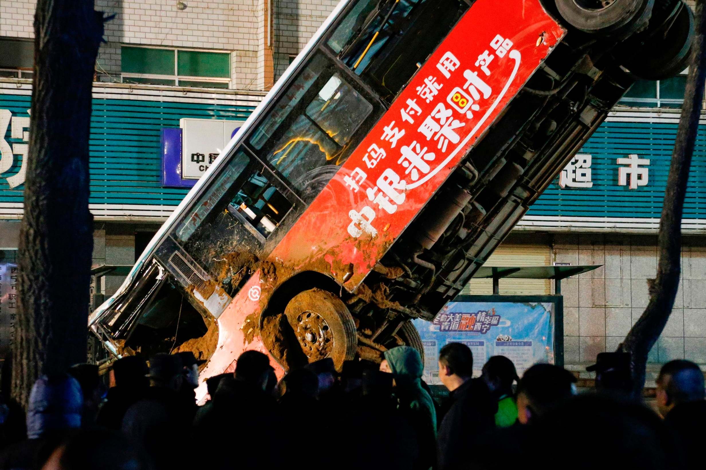 Chinese rescuers watch on as the bus is lifted out of the sinkhole