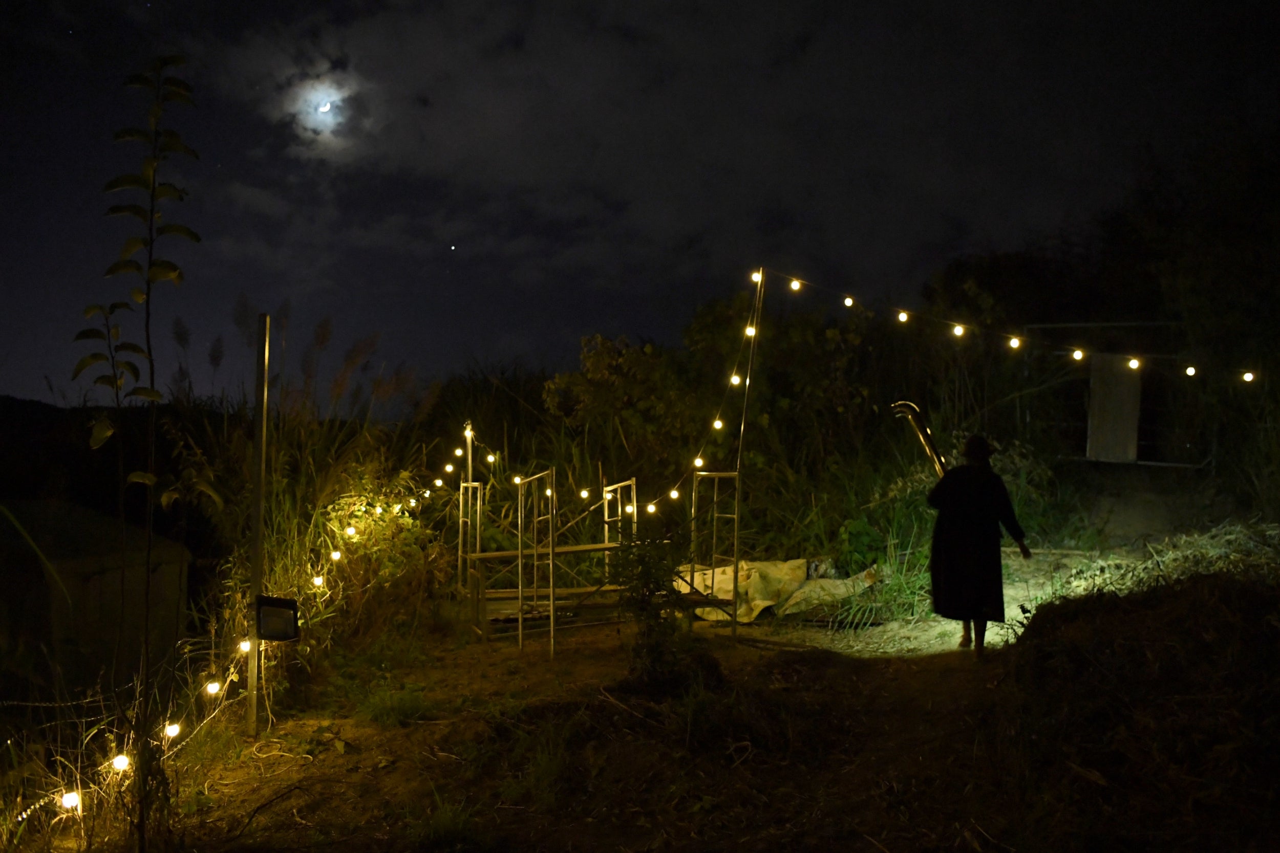 Xing Zhen walks under a string of lights at AnotherCommunity