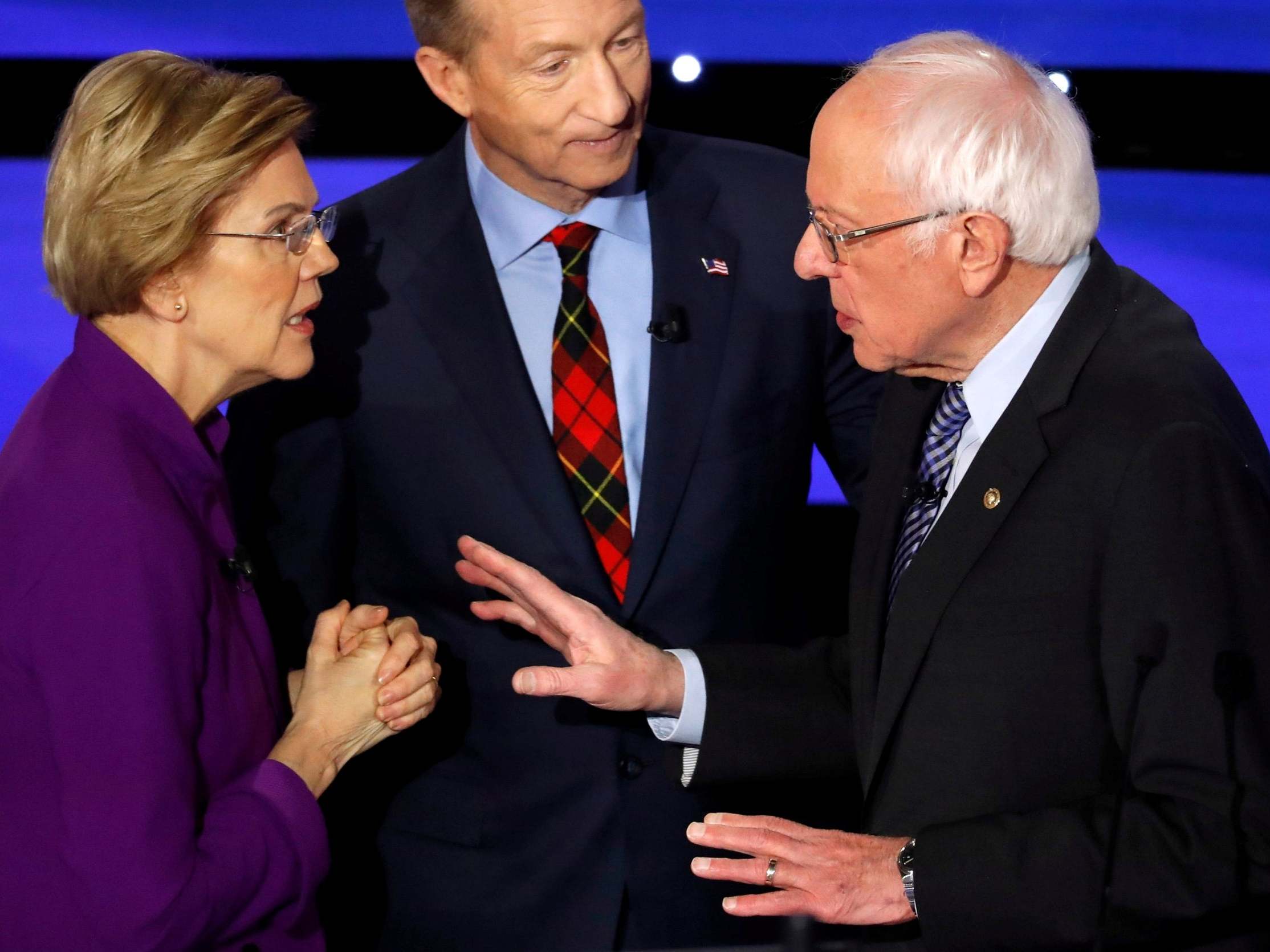 Elizabeth Warren speaks with Bernie Sanders as billionaire activist Tom Steyer listens after the seventh Democratic 2020 presidential debate at Drake University in Des Moines, Iowa on 14 January 2020