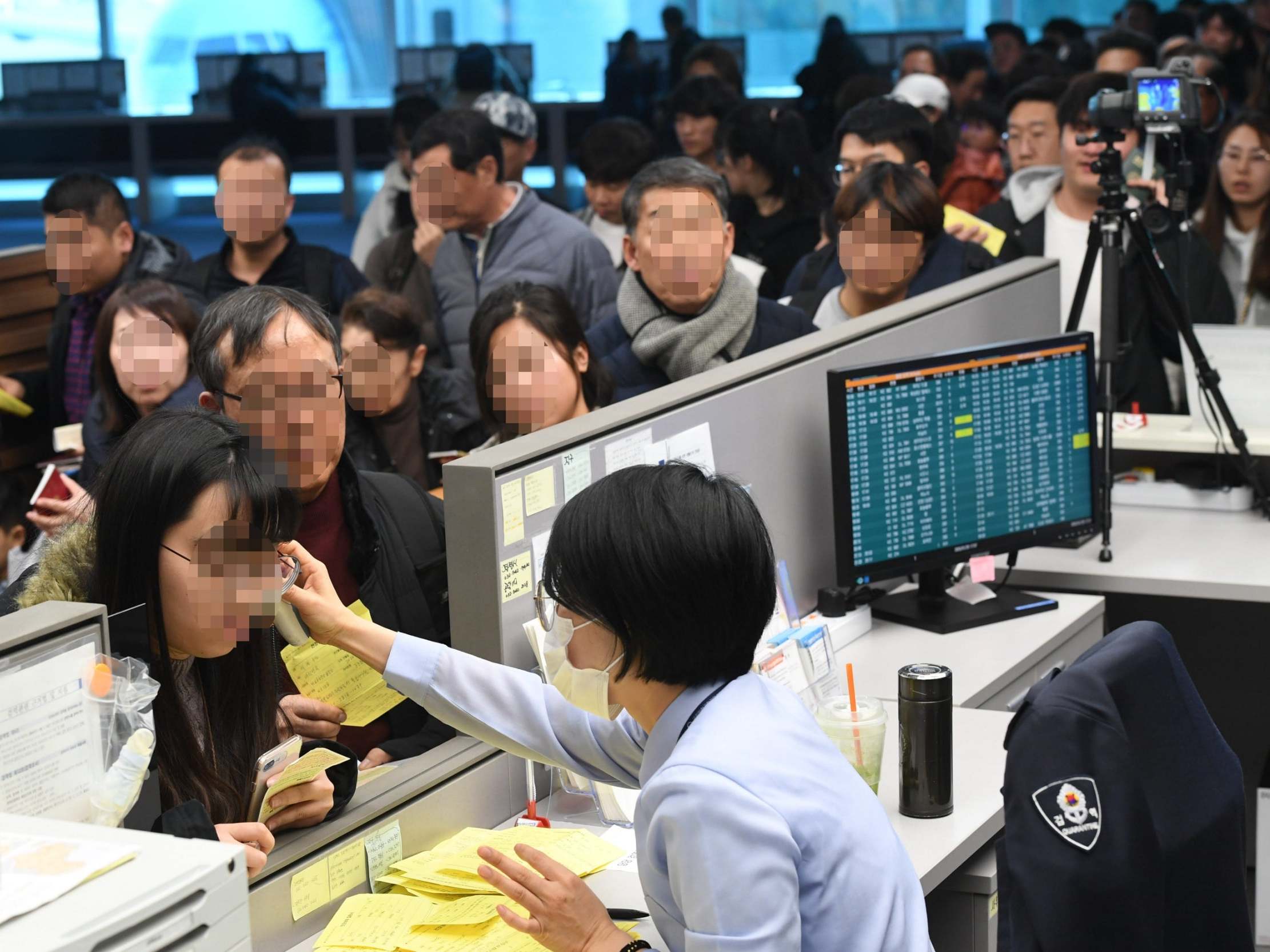 A quarantine officer at Incheon International Airport, west of Seoul, South Korea, uses an electronic thermometer to check the temperature of passengers arriving by plane from Wuhan, China, 20 January, 2020.