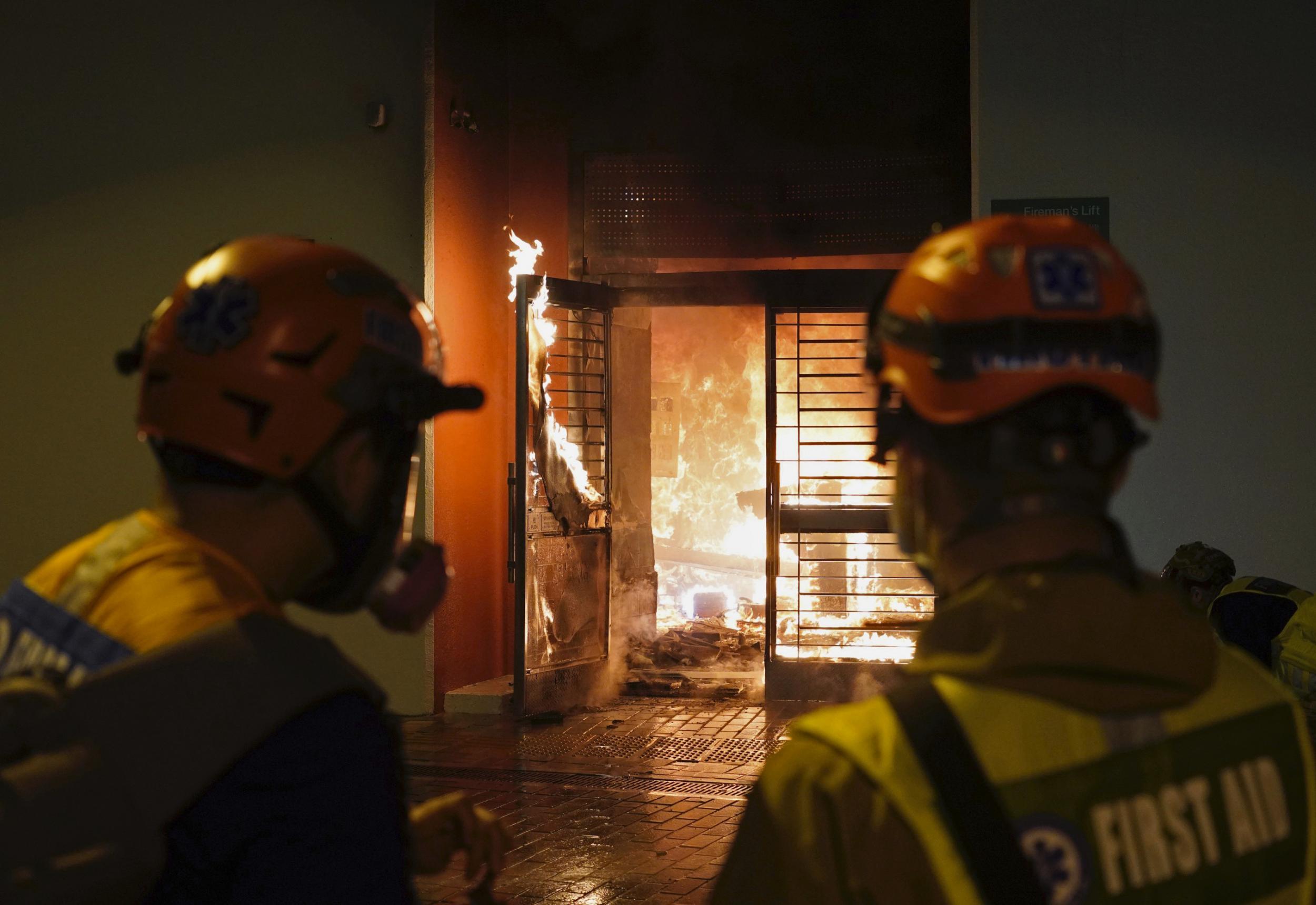 First aid volunteers try to extinguish a fire set by local residents at a building of the Fai Ming Estate, in Fanling district of Hong Kong Sunday Jan. 26 2020 (AP)