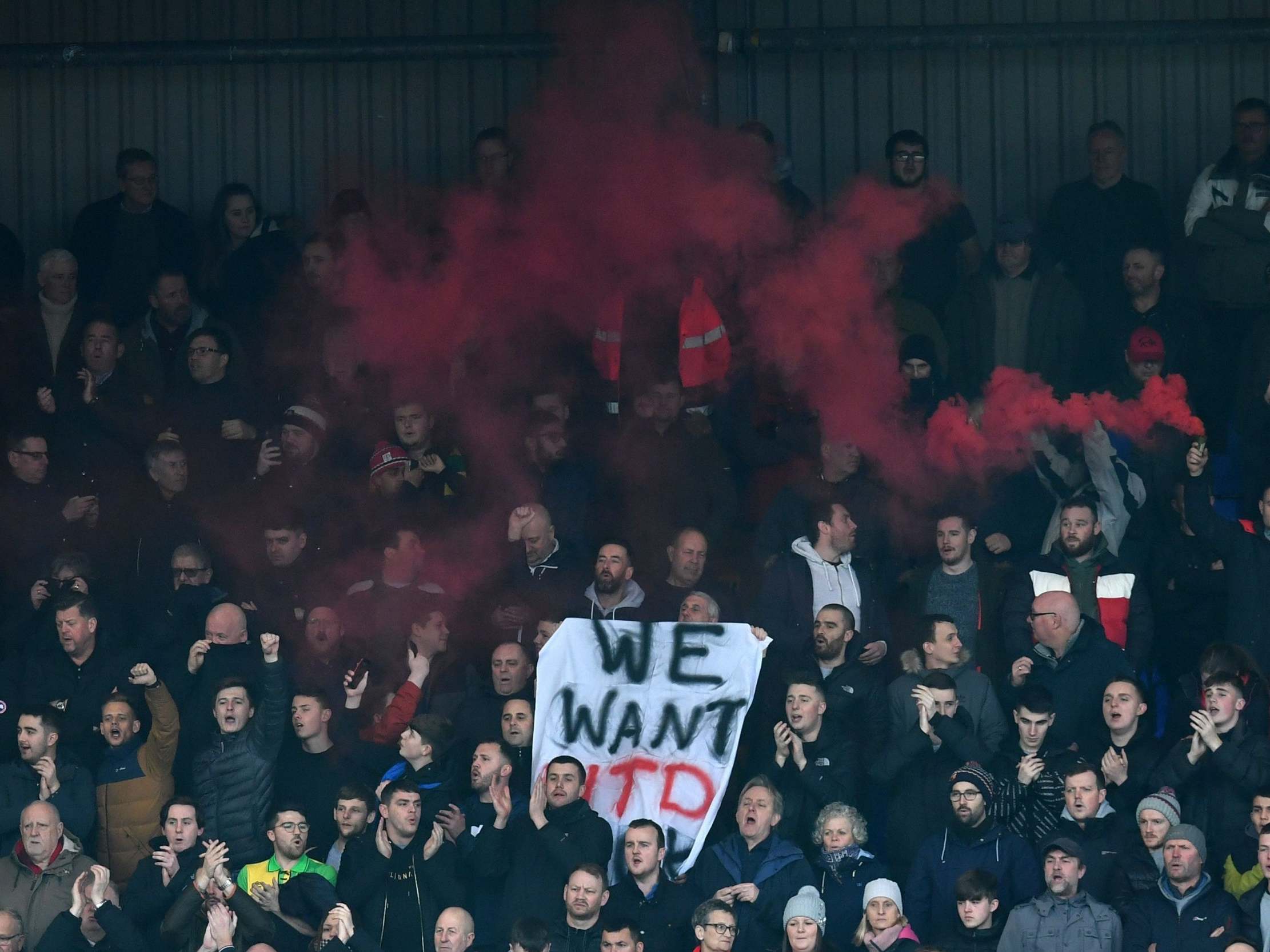 Supporters hold a banner which reads: 'We want Utd back'