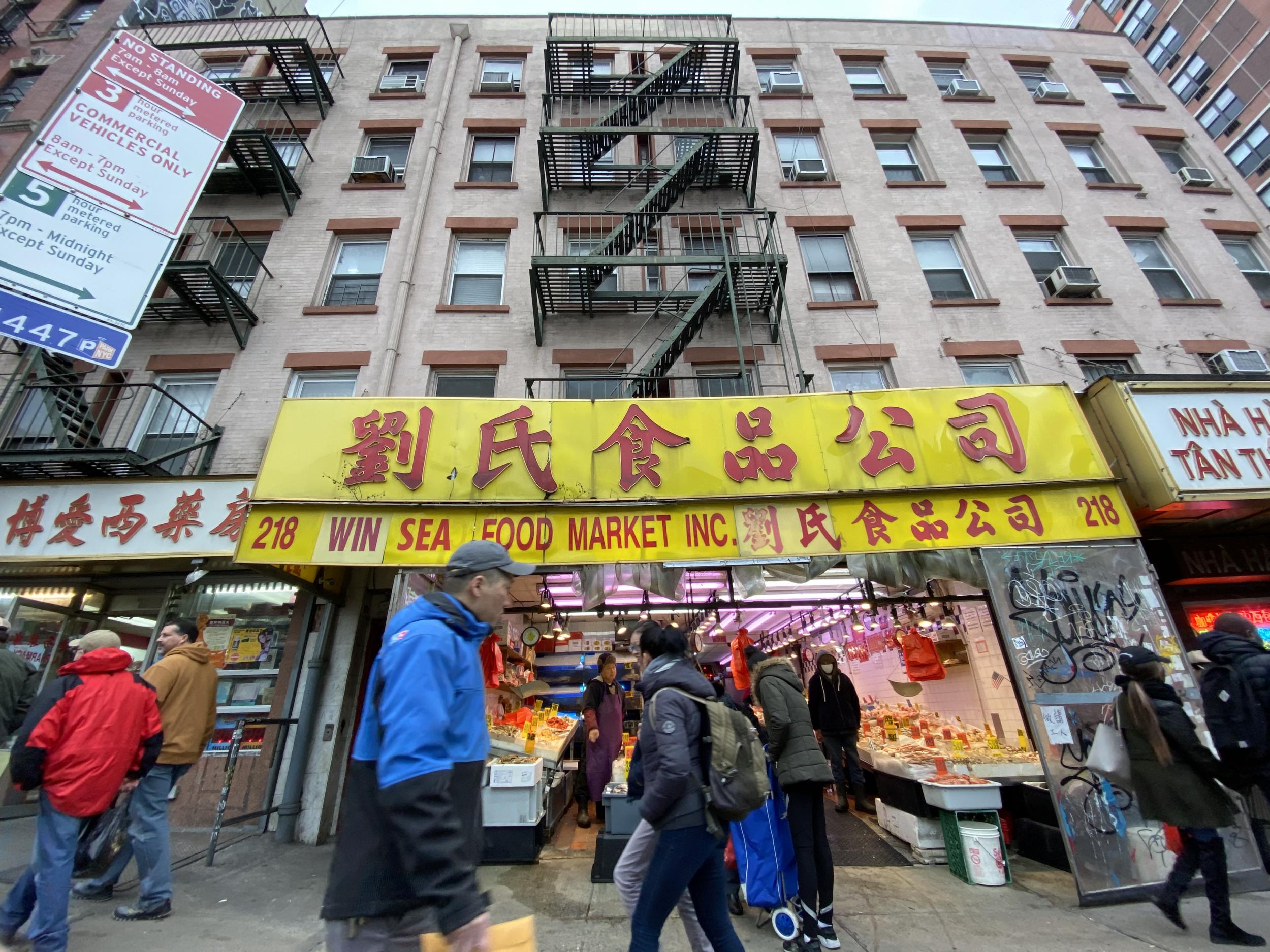 Pedestrians pass by outside of a Chinatown fish market