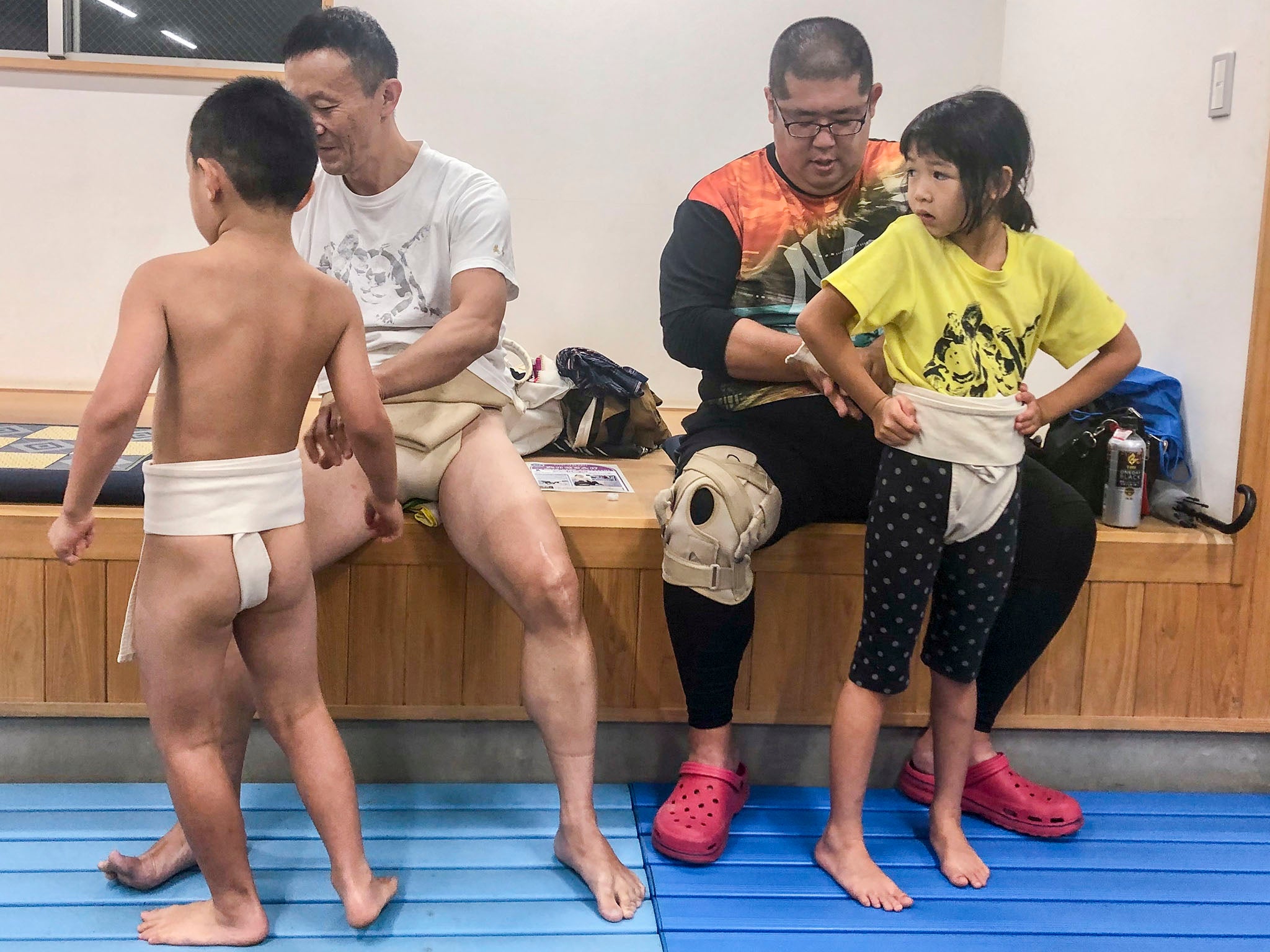 Ken Terauchi, program director of Tokyo’s Ota Arashi dojo, and Takamitsu Sekiguchi, the dojo’s coach, help young wrestlers wrap their mawashi before a practice session