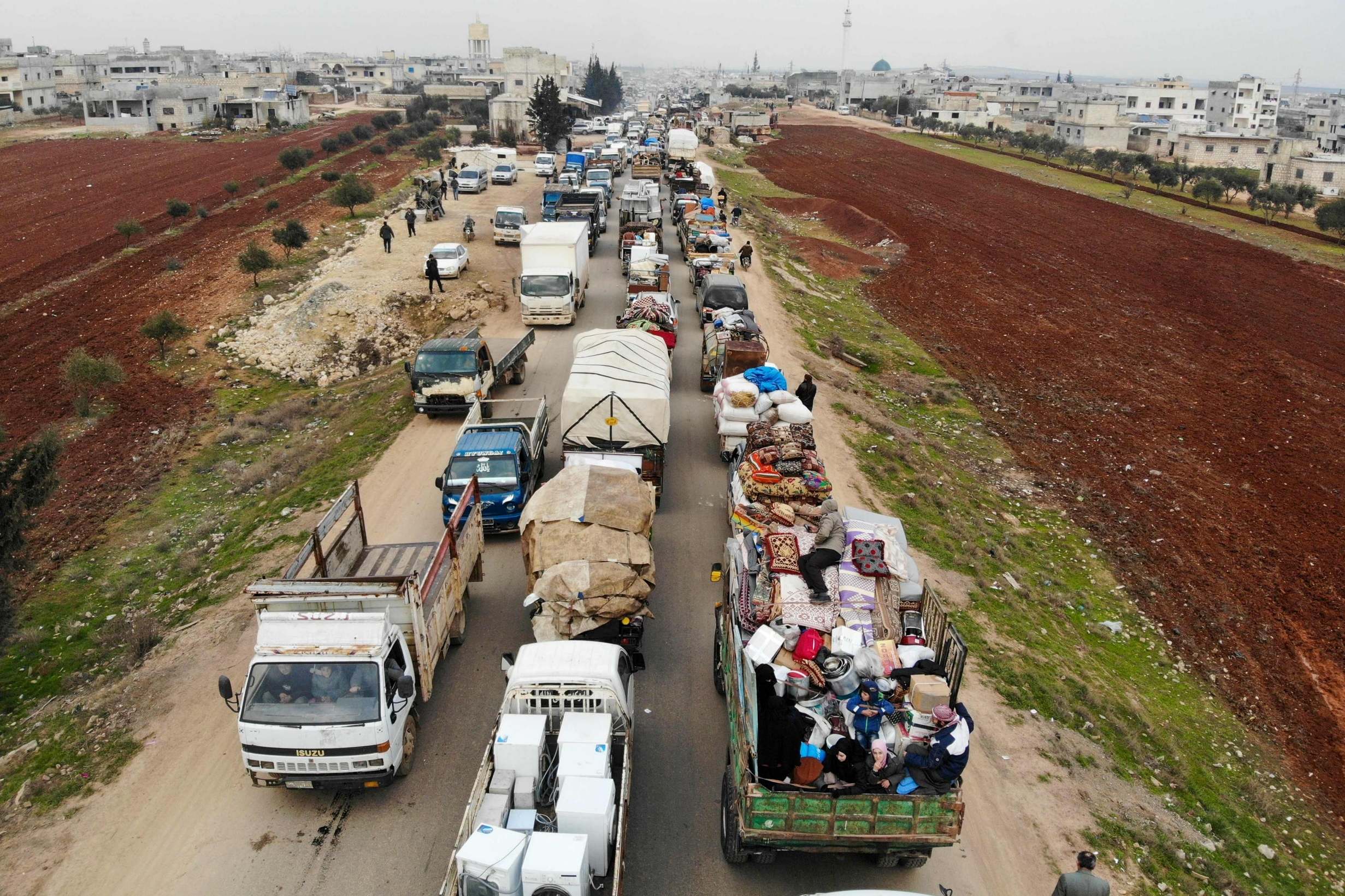 Civilians drive through Hazano in the northern countryside of Idlib as they flee the latest offensive by President Assad's regime