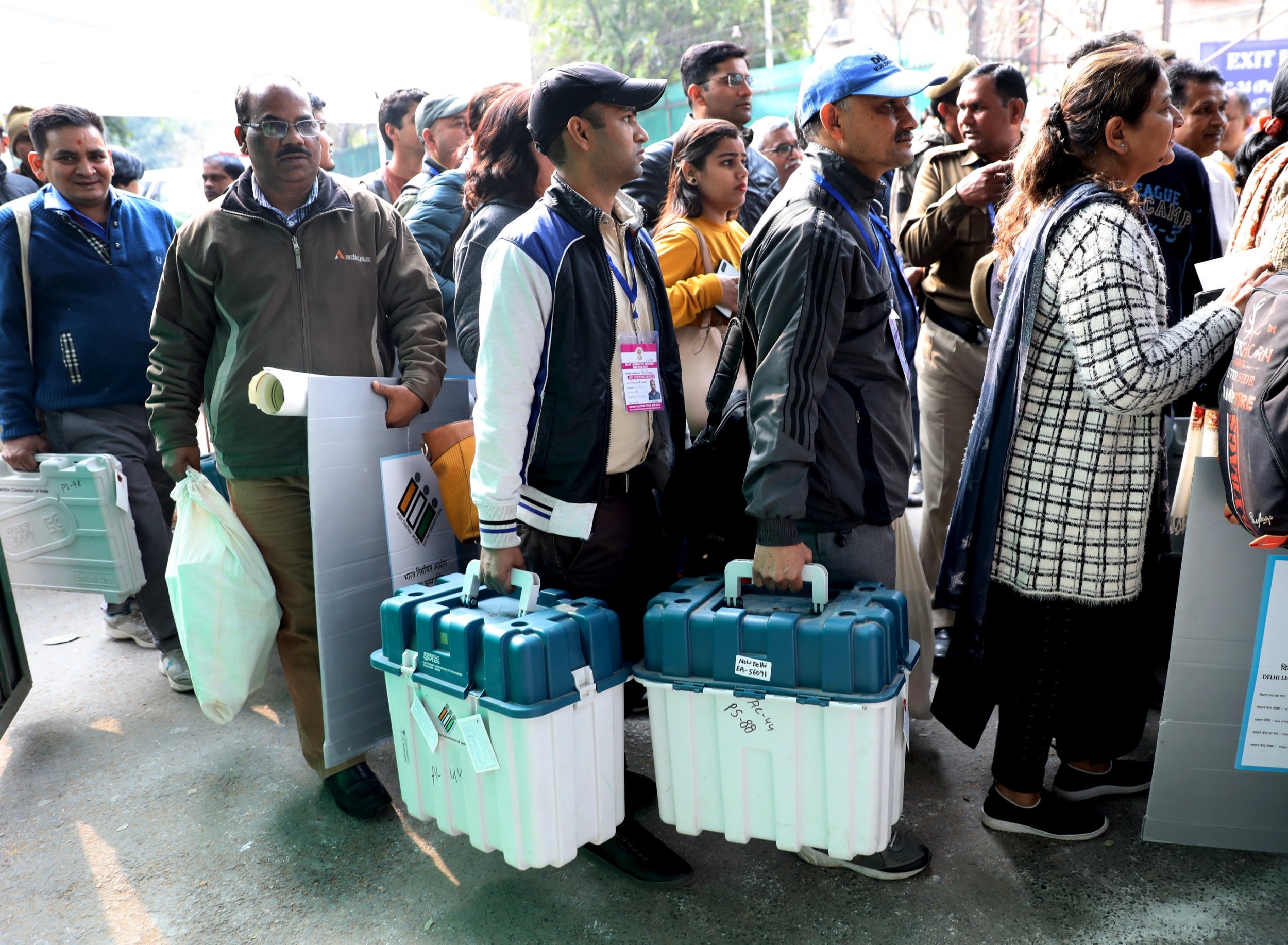 Indian polling officials carry Electronic Voting Machines (EVM) on an official bus on its way to polling stations in Delhi