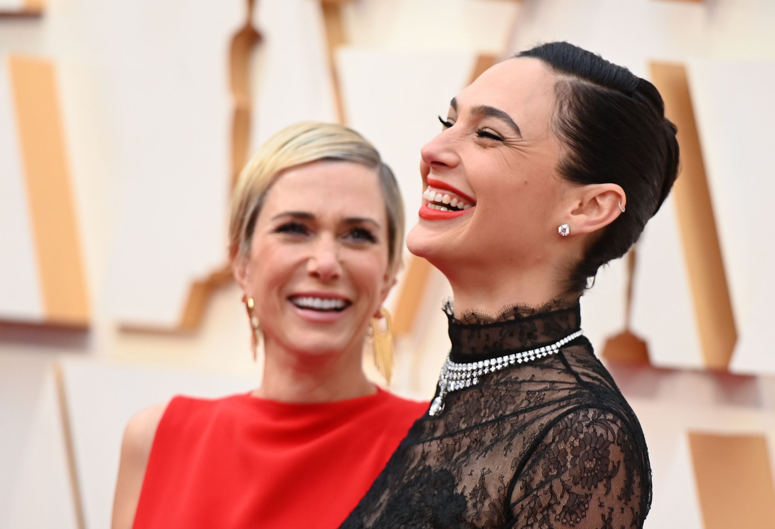 The <i>Wonder Woman 1984</i> co-stars laughed as they posed together on the red carpet, Wiig in red and Gadot in black lace.