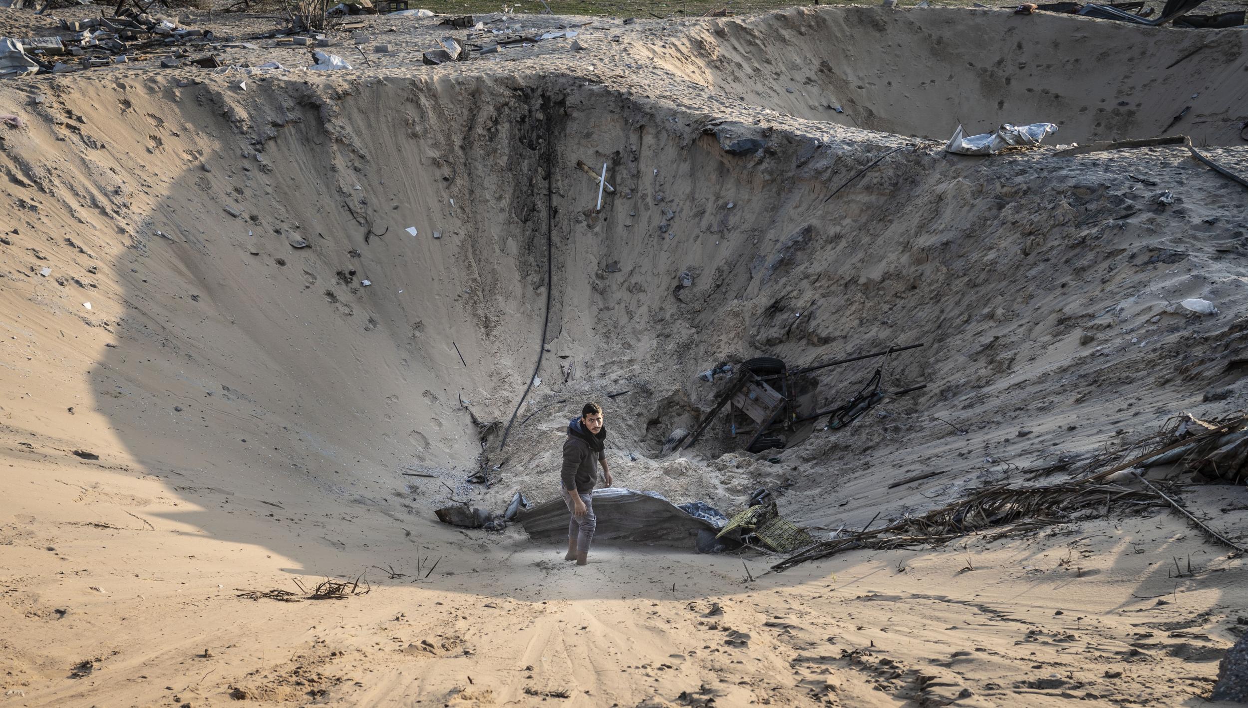 Awad Abu Mismeh, 20, inside the crater of what once was his father's home after an Israeli airstrike