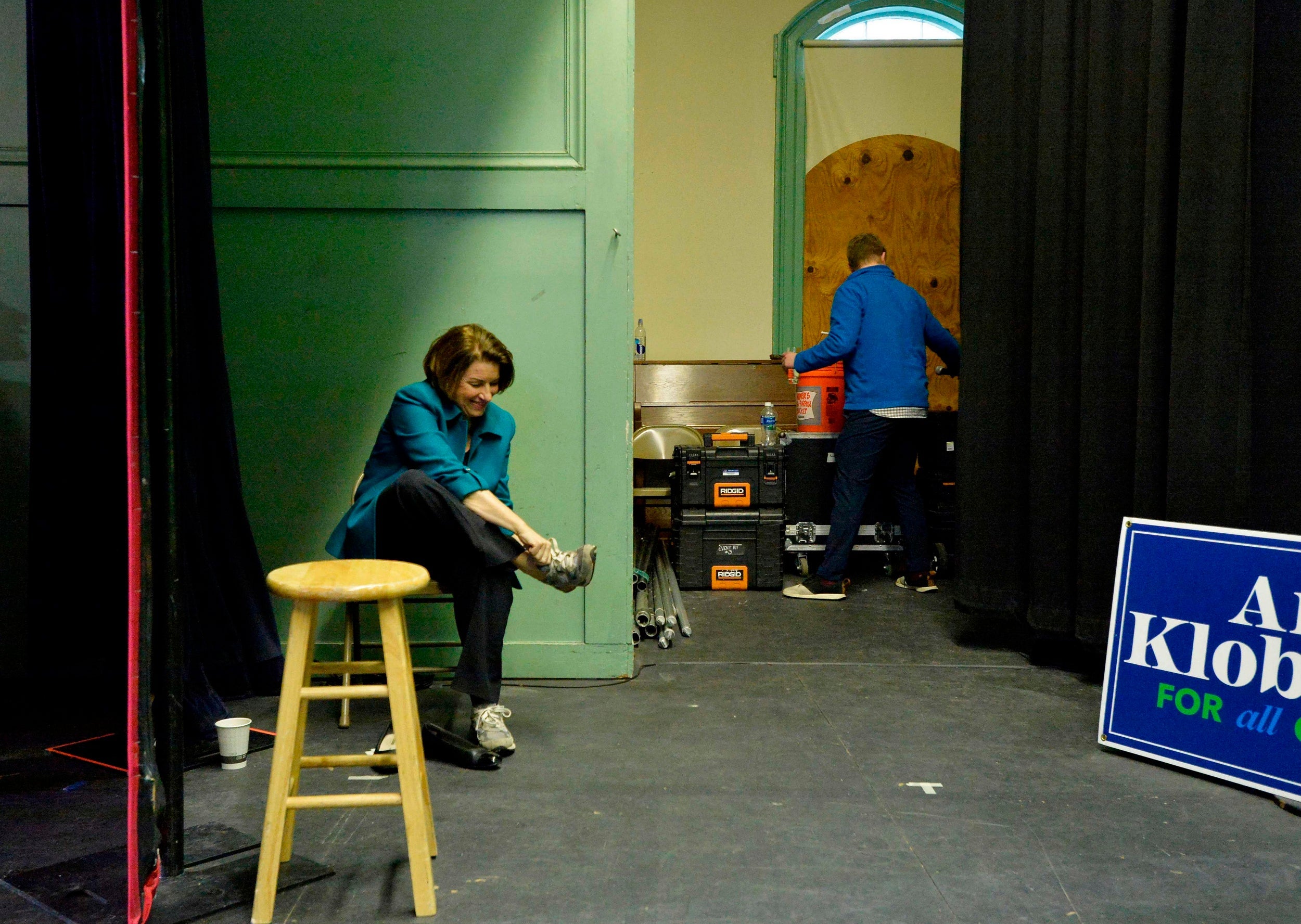 Klobuchar changes her shoes backstage after giving a speech in New Hampshire yesterday (AFP)