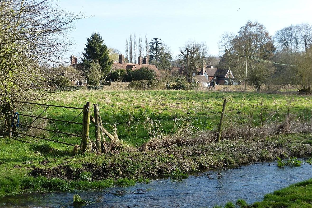 View across a swollen burn near houses on the southwestern edge of Chesham