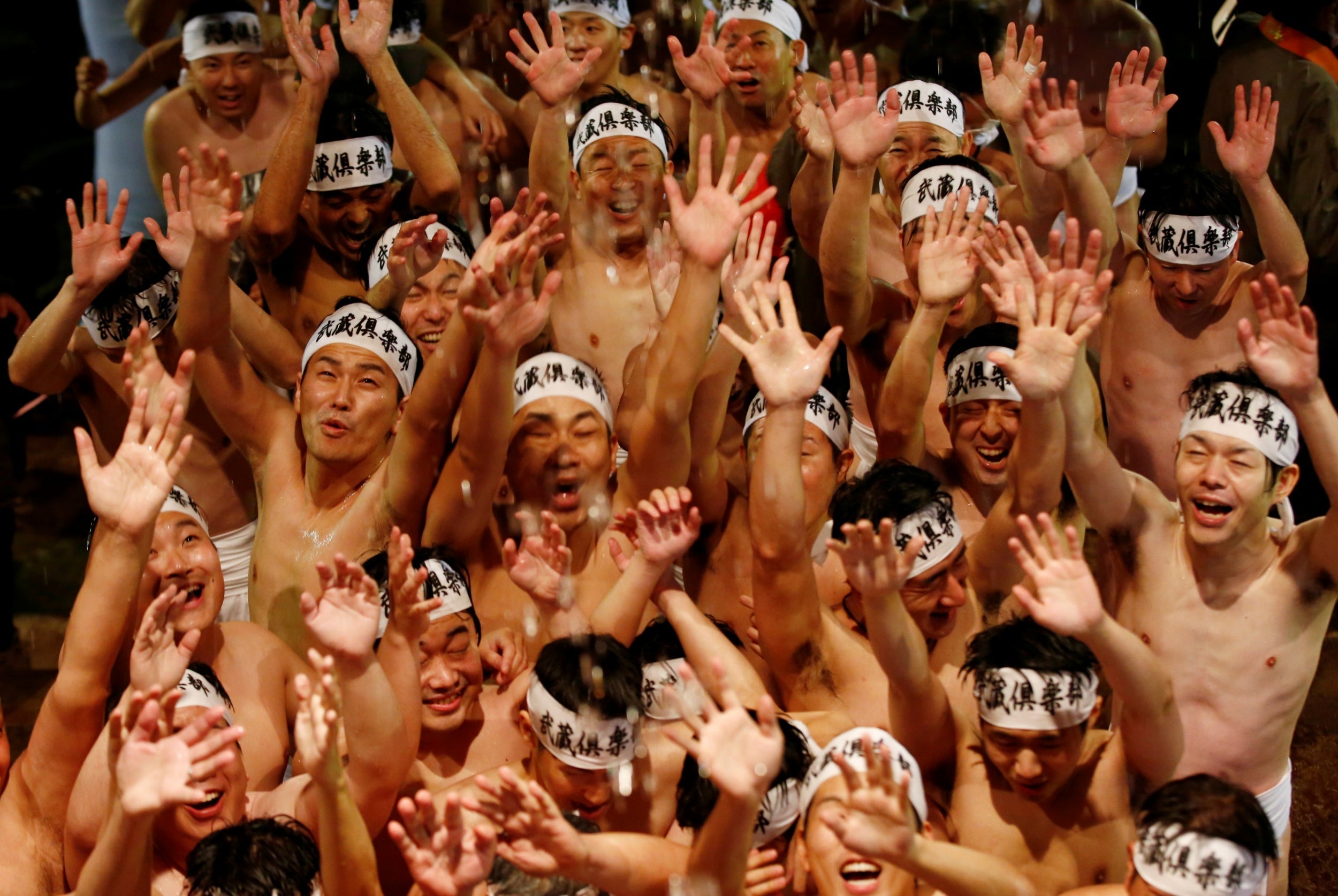 Men dressed in loincloths react as a priest splashes water on them before they prepare to snatch a wooden stick called ‘shingi‘