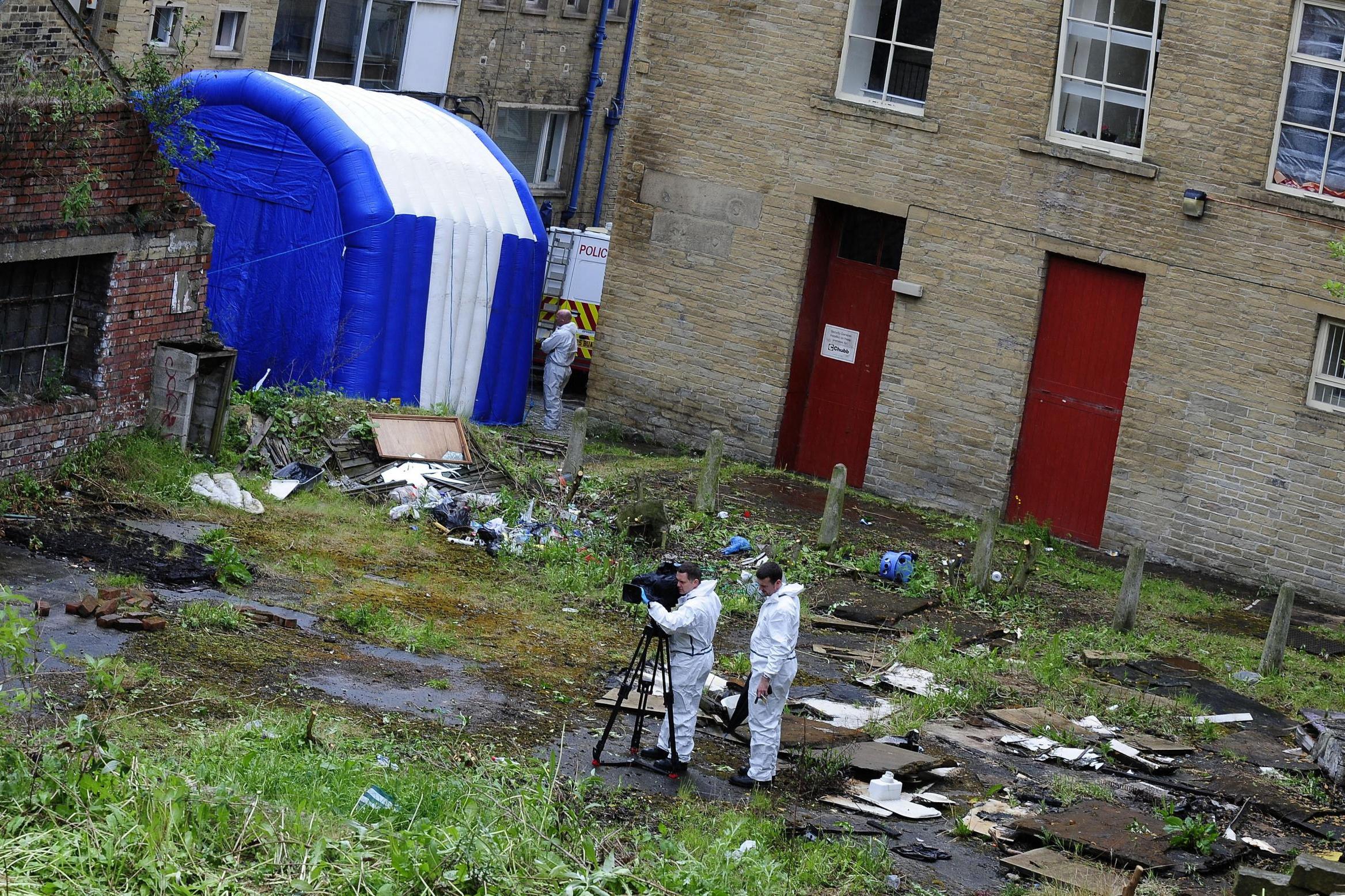 Forensics officers work in the rear garden of the flats