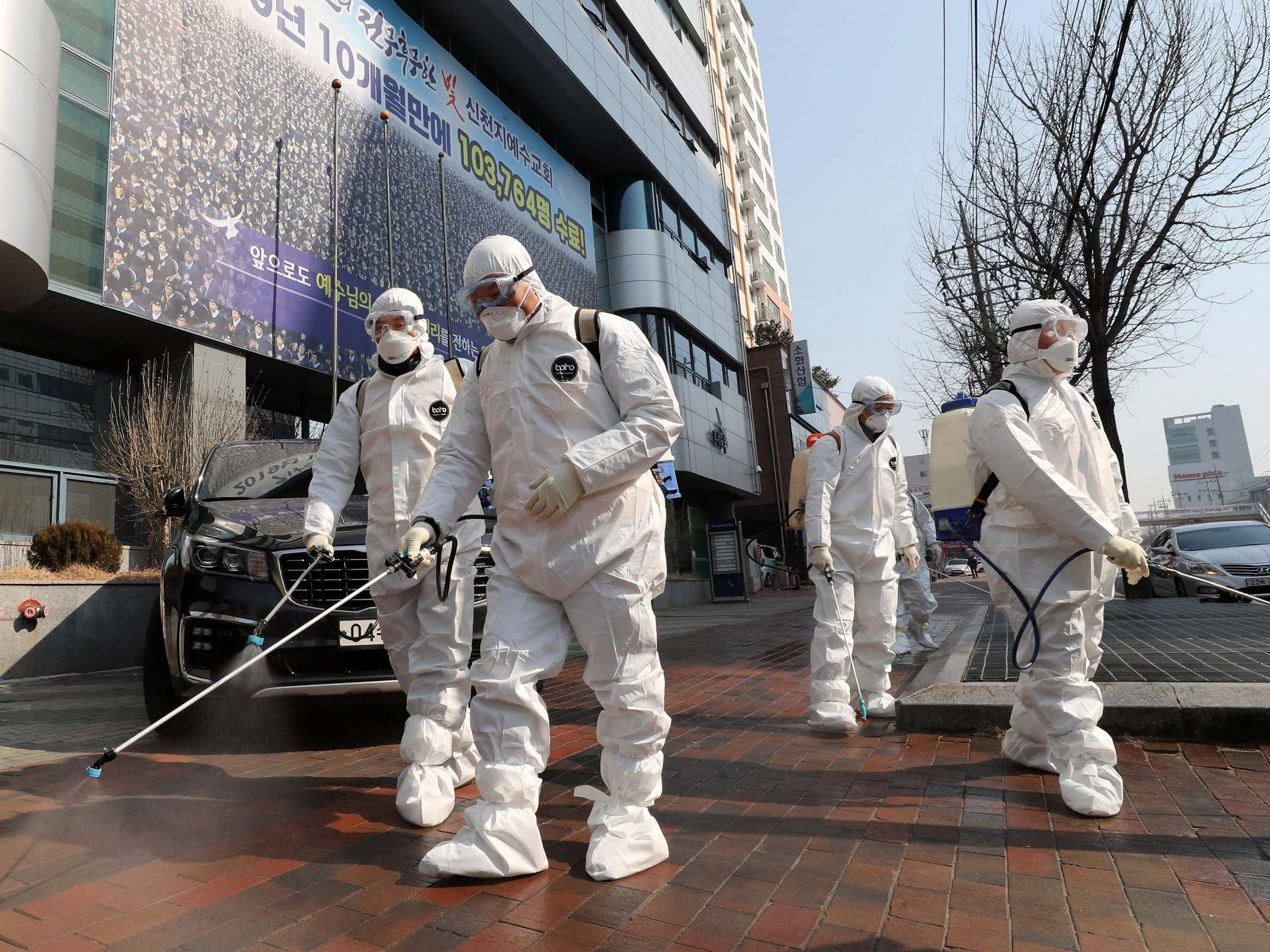 Workers spray disinfectant in front of a church in Daegu, South Korea