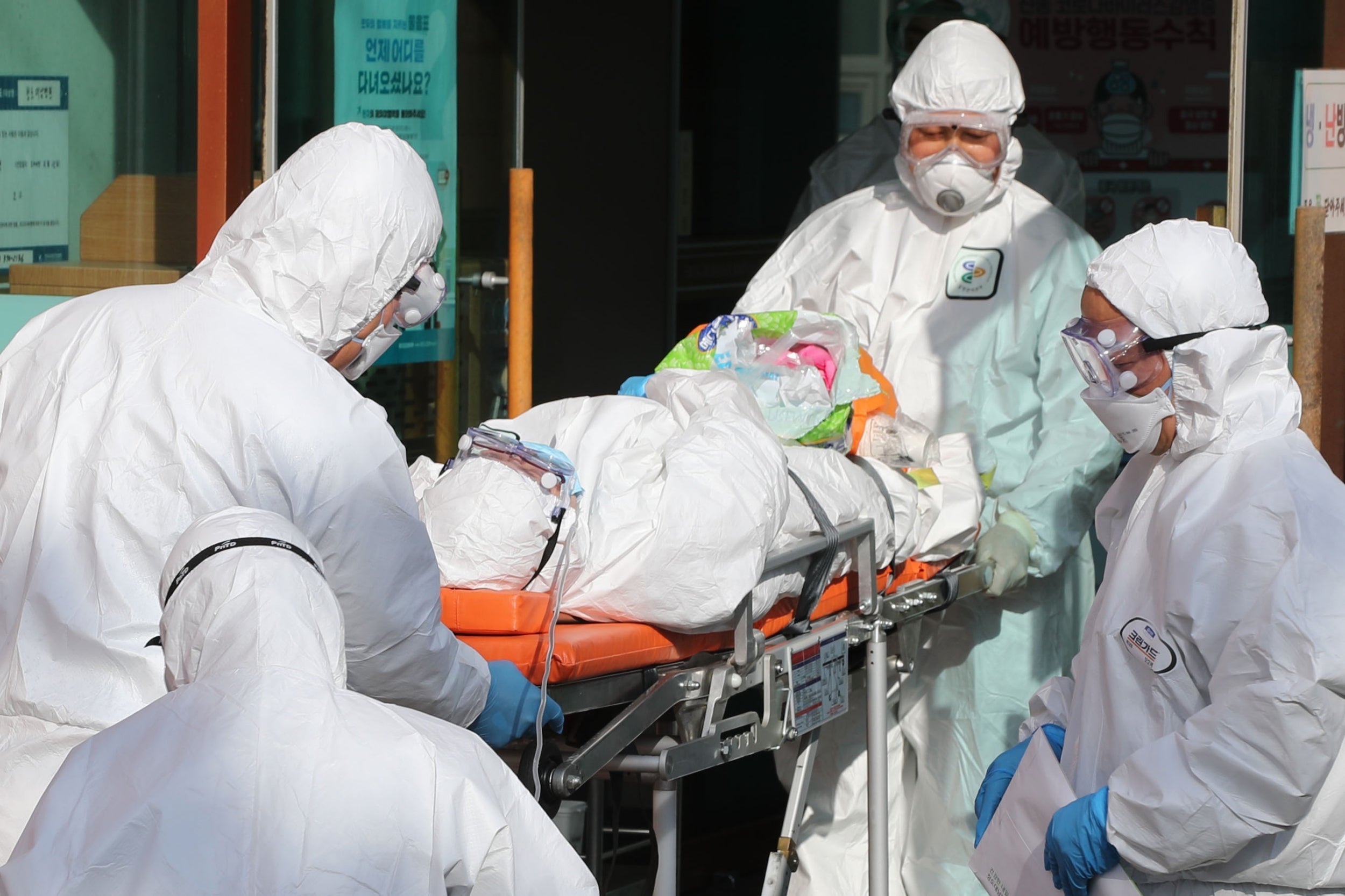 Medical workers wearing protective gear transfer a suspected coronavirus patient to another hospital from Daenam Hospital