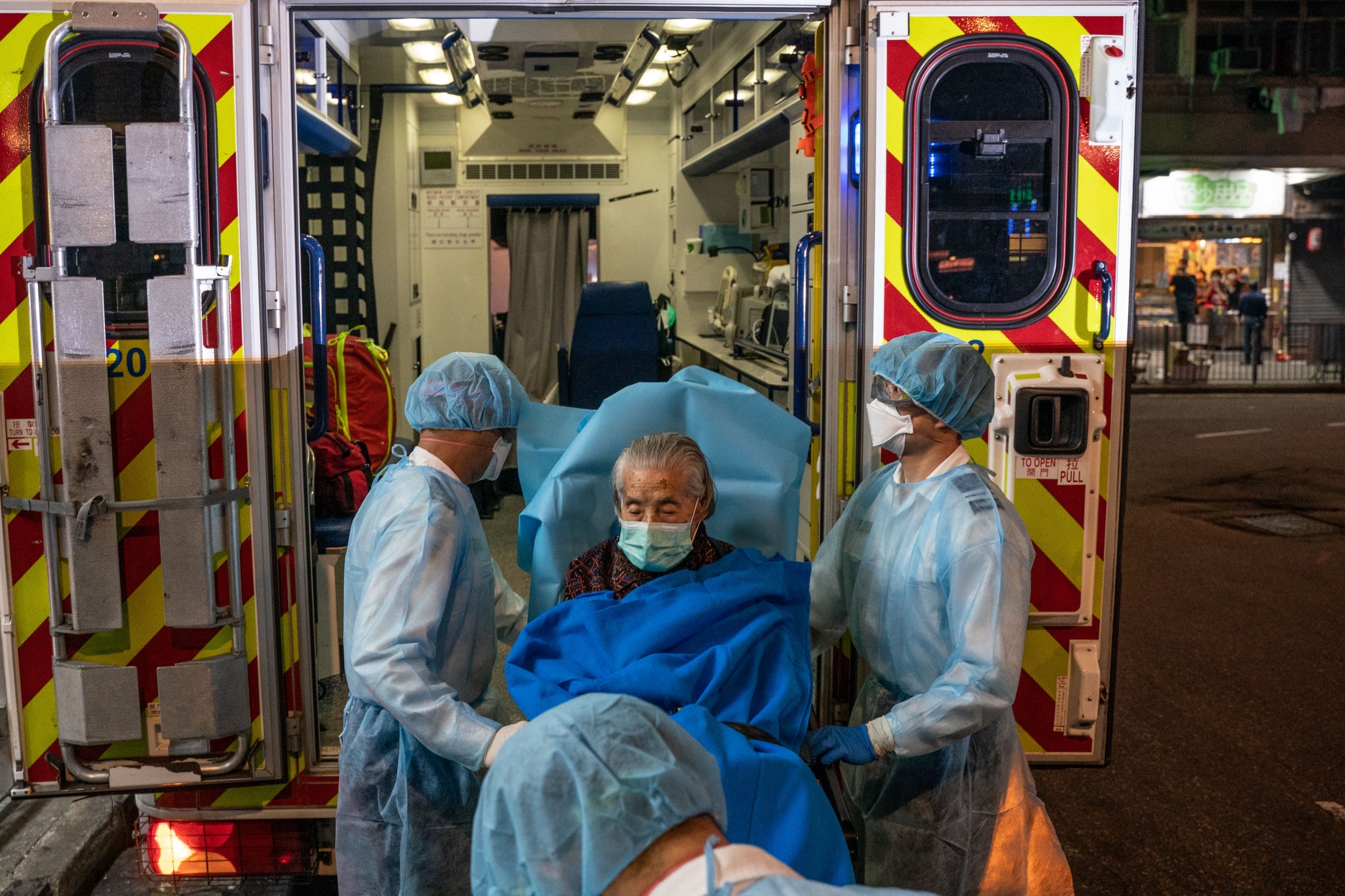 Paramedics wearing personal protective equipment carry patient on a stretcher on to an ambulance in North Point district in Hong Kong, China