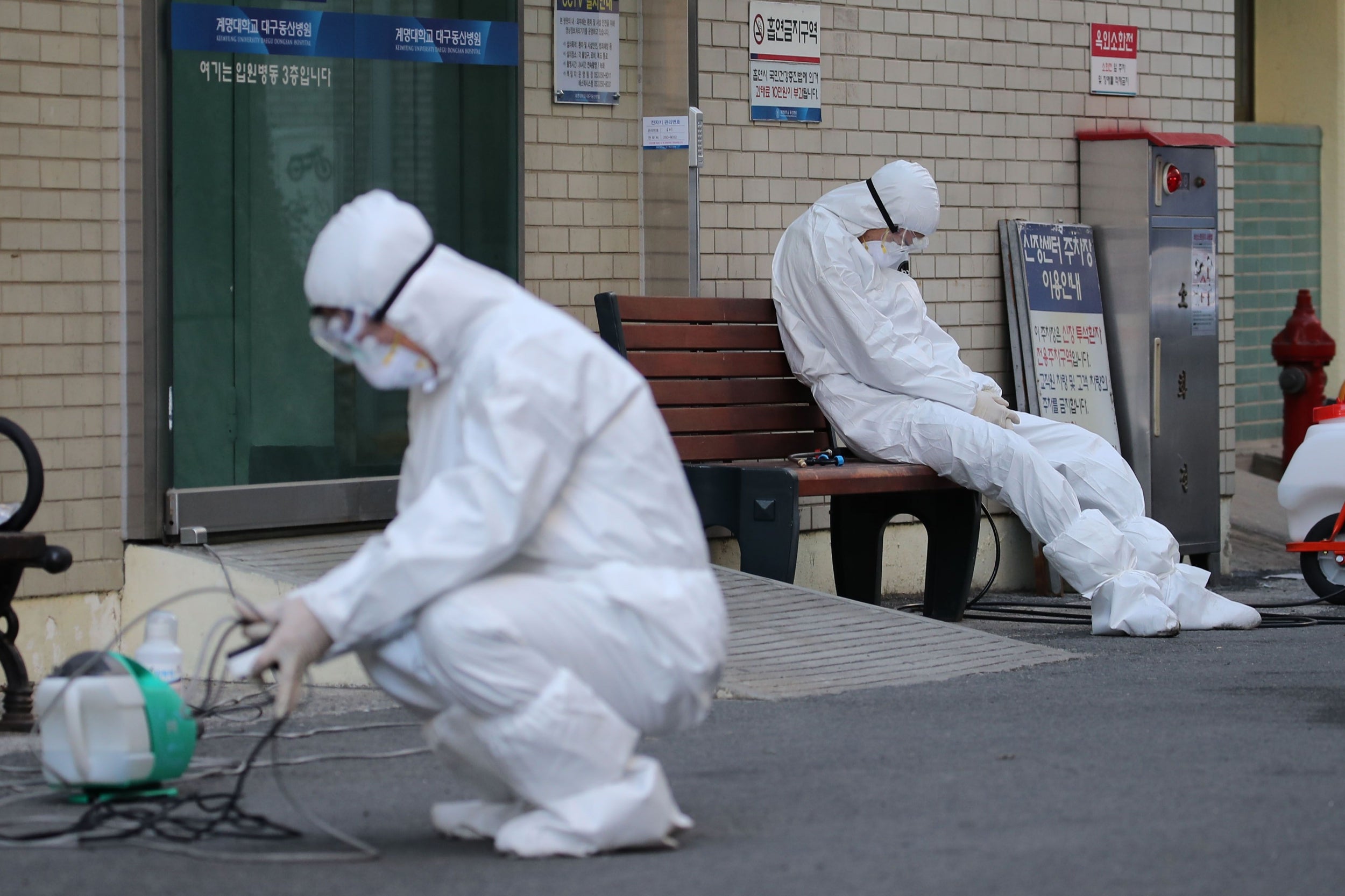 A medical worker wearing protective gear takes a rest as he waits for ambulances carrying patients infected with the COVID-19 coronavirus at an entrance of a hospital in Daegu, South Korea