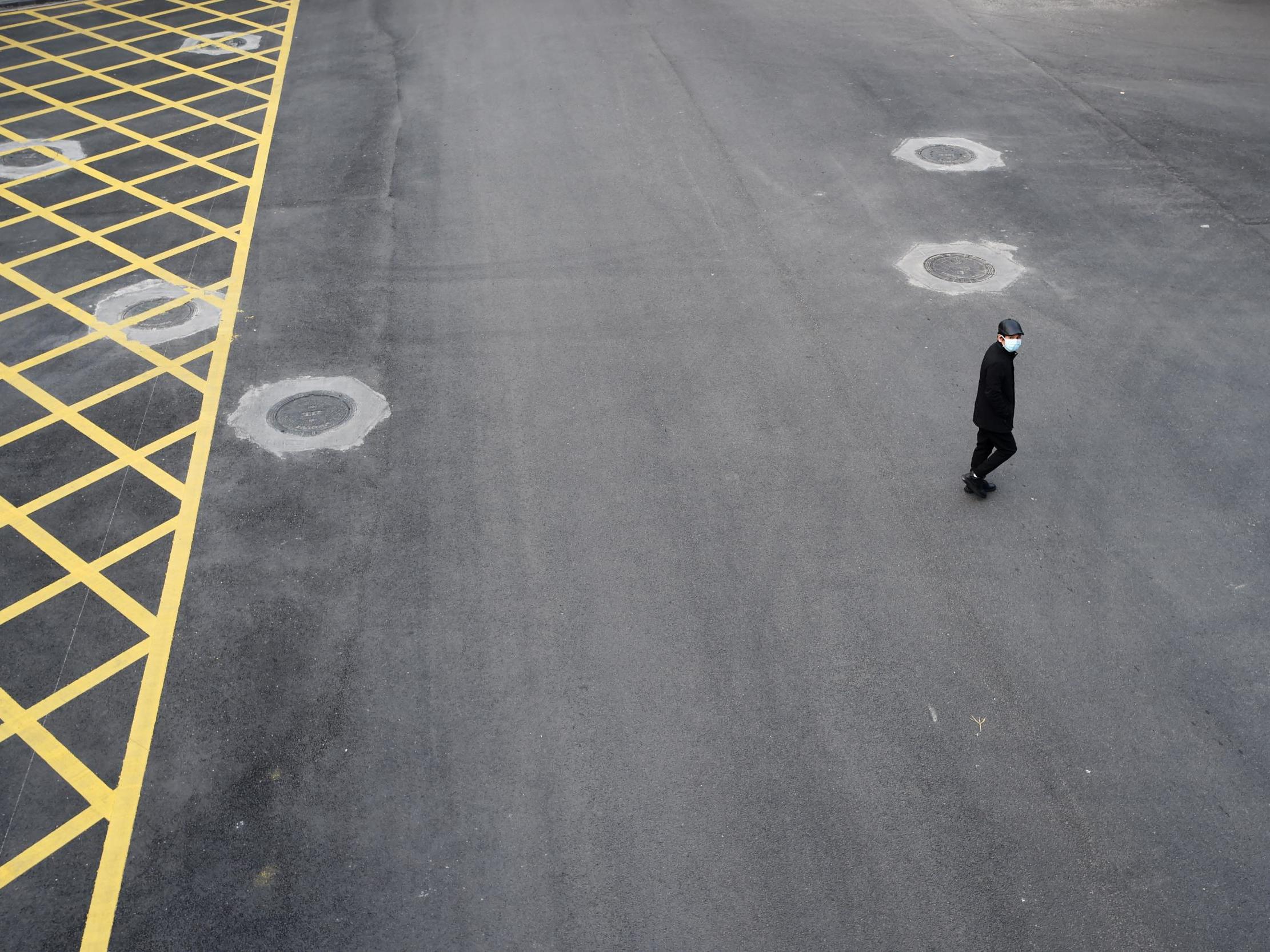 A man wearing a face mask crosses a road in Wuhan, the epicentre of the novel coronavirus outbreak.