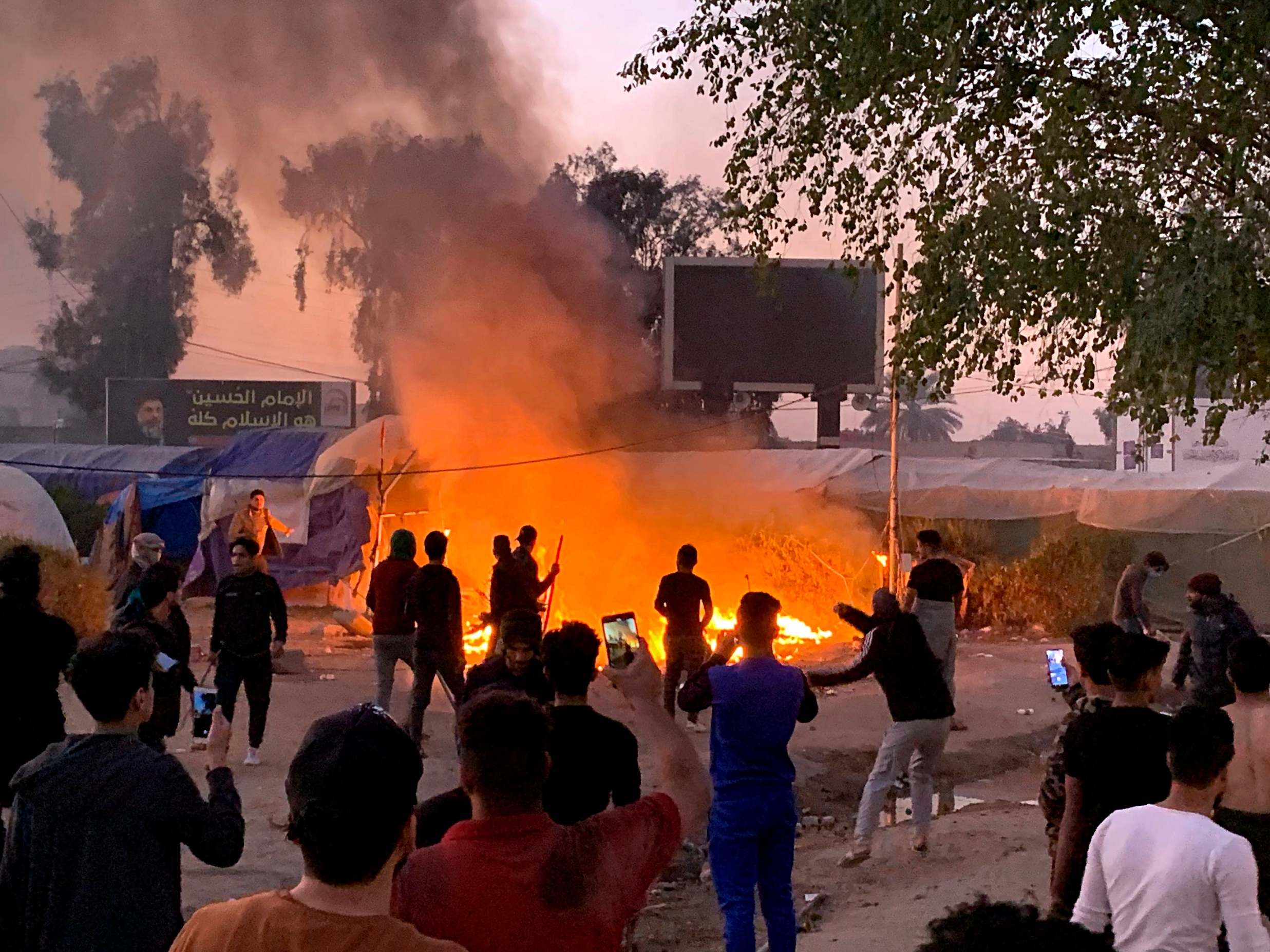 Anti-government protesters attempt to extinguish their burning tents in Najaf: many have been shot dead and dozens wounded in the clashes