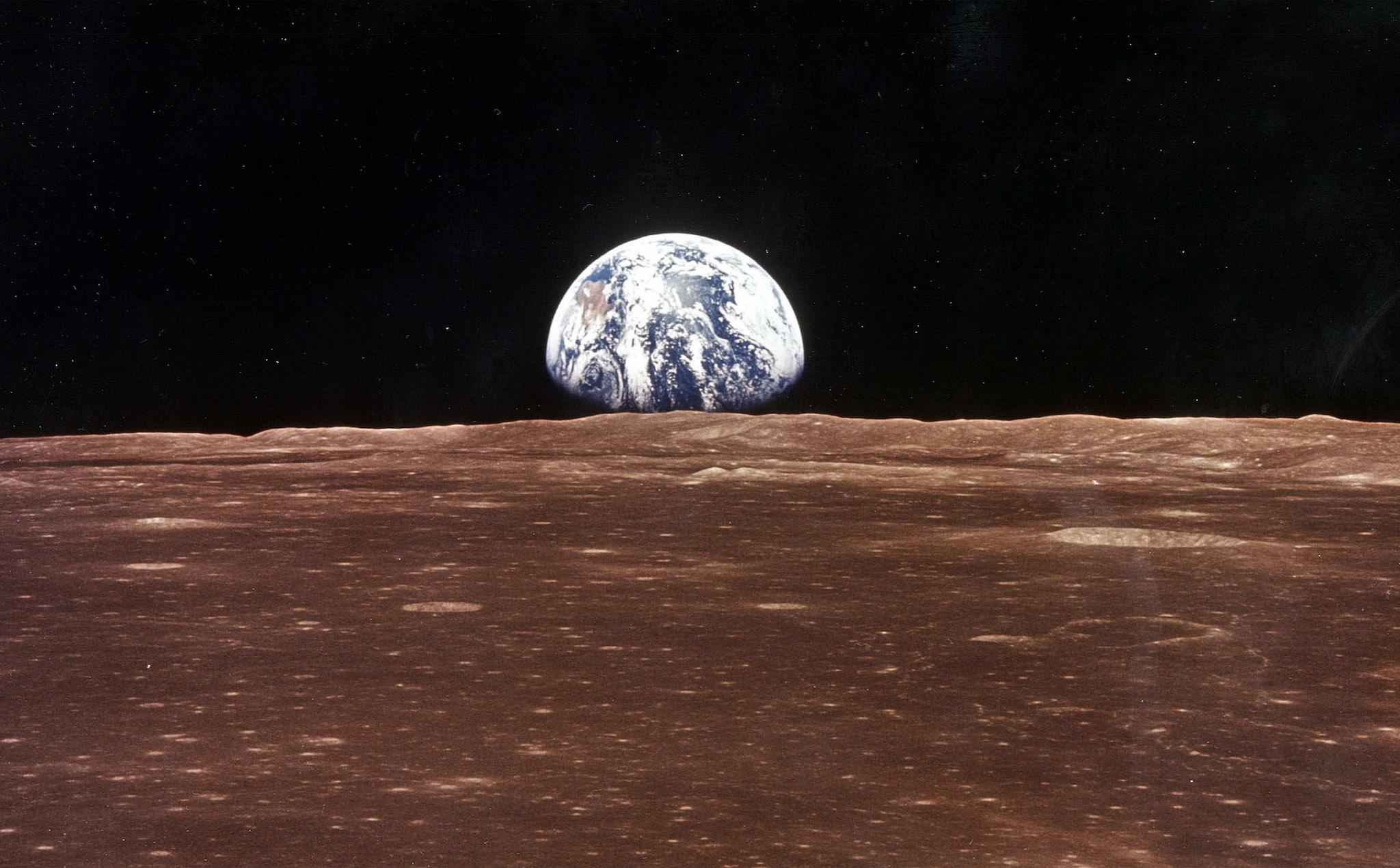 A view of the Earth appears over the Lunar horizon as the Apollo 11 Command Module comes into view of the Moon before Astronatus Neil Armstrong and Edwin Aldrin Jr. leave in the Lunar Module, Eagle, to become the first men to walk on the Moon's surface