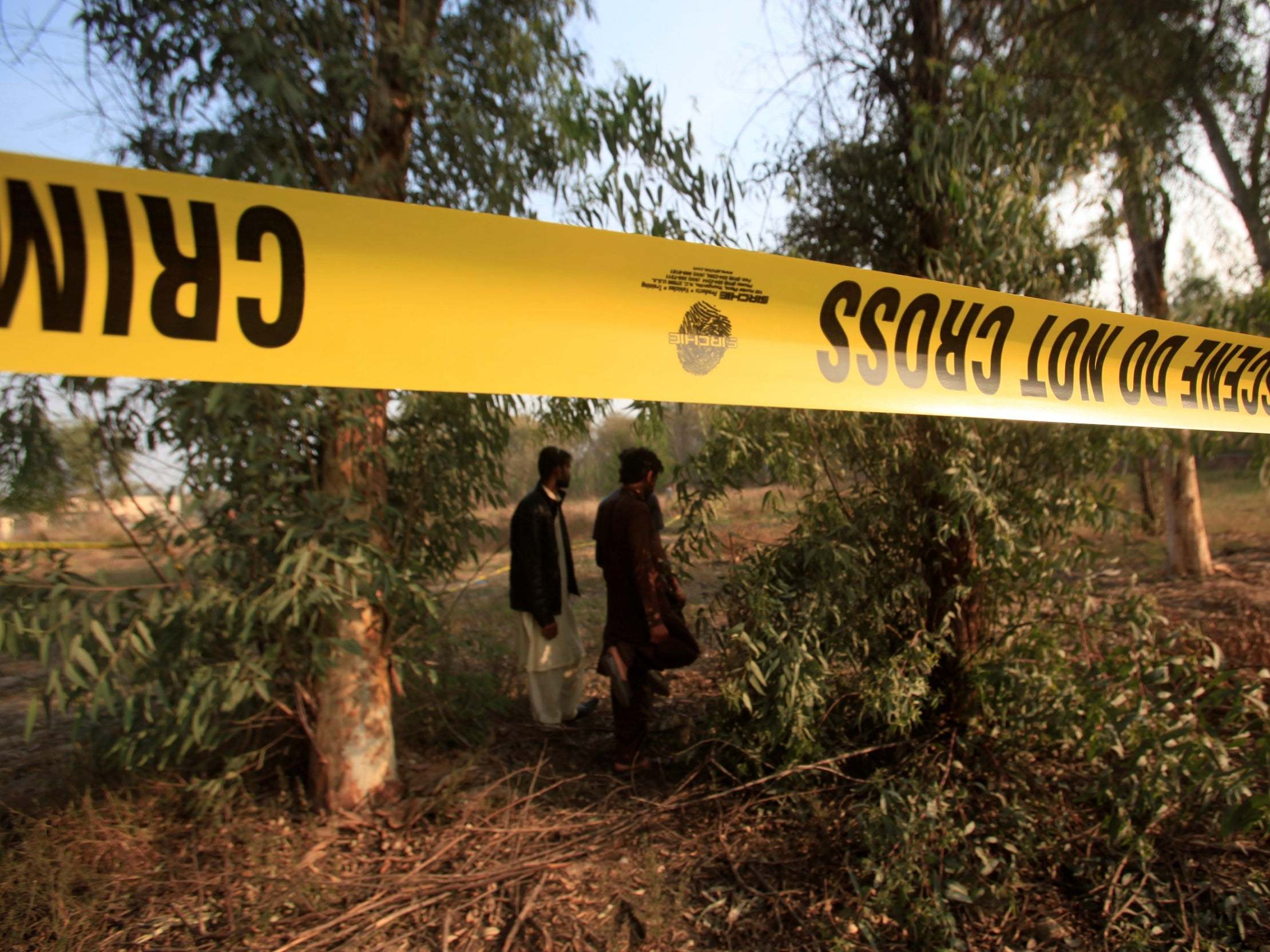 Men walk near a cordoned area at a safari park in Lahore, Pakistan, after remains of a missing teenager were found