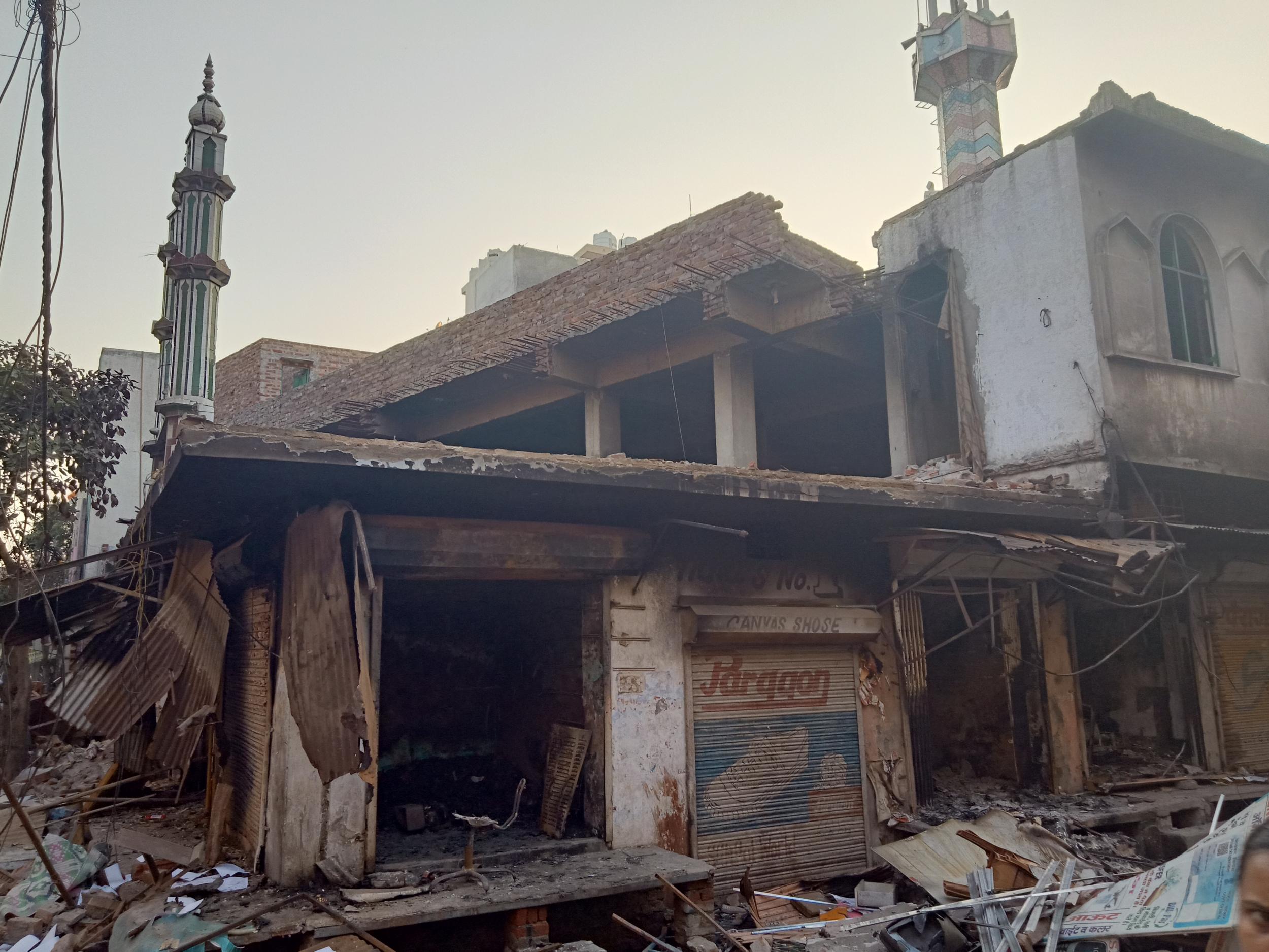 Muslim homes and businesses stand broken and charred next to attacked mosque