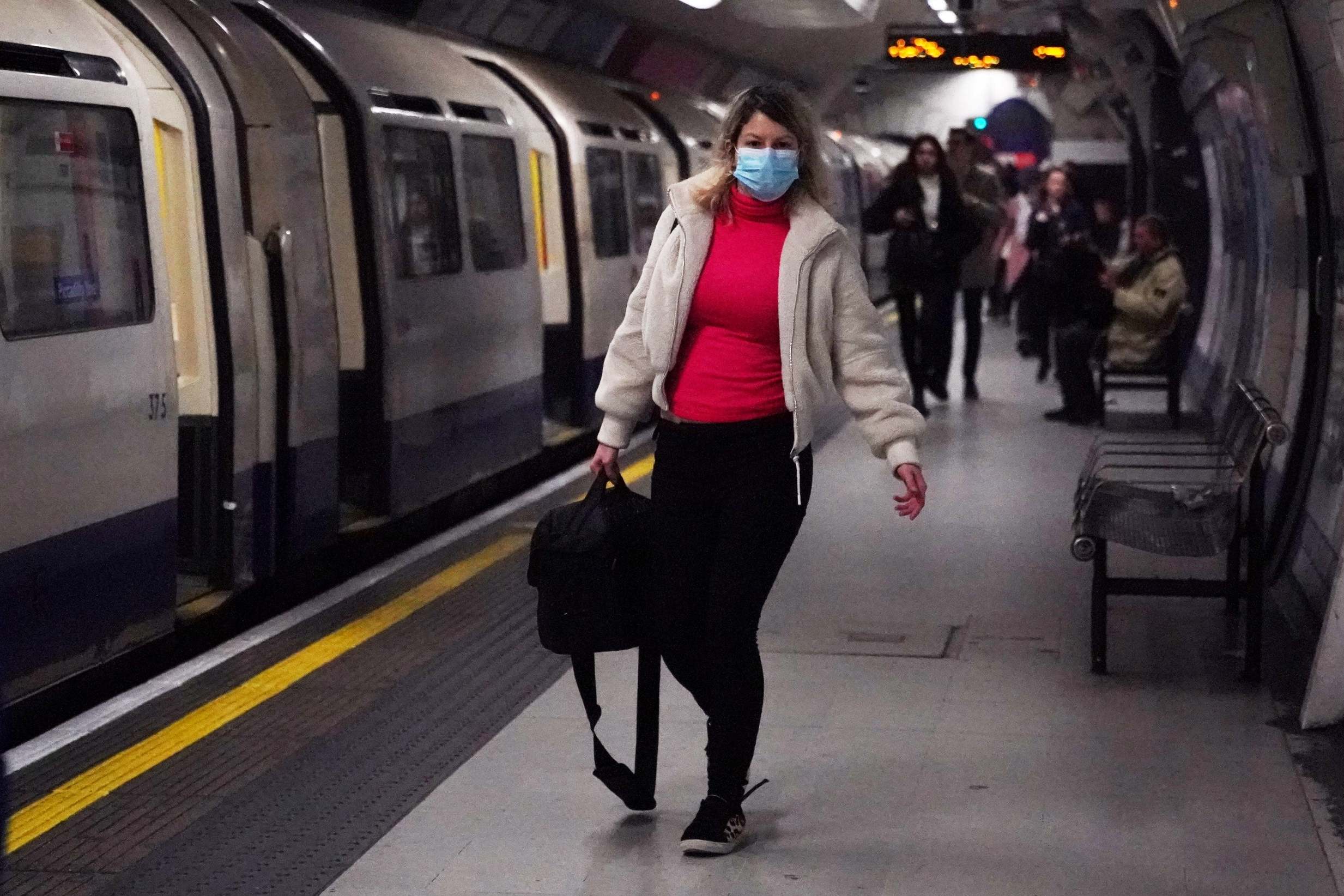 A woman wearing a protective mask walks along the platform at Leicester Square underground station in London