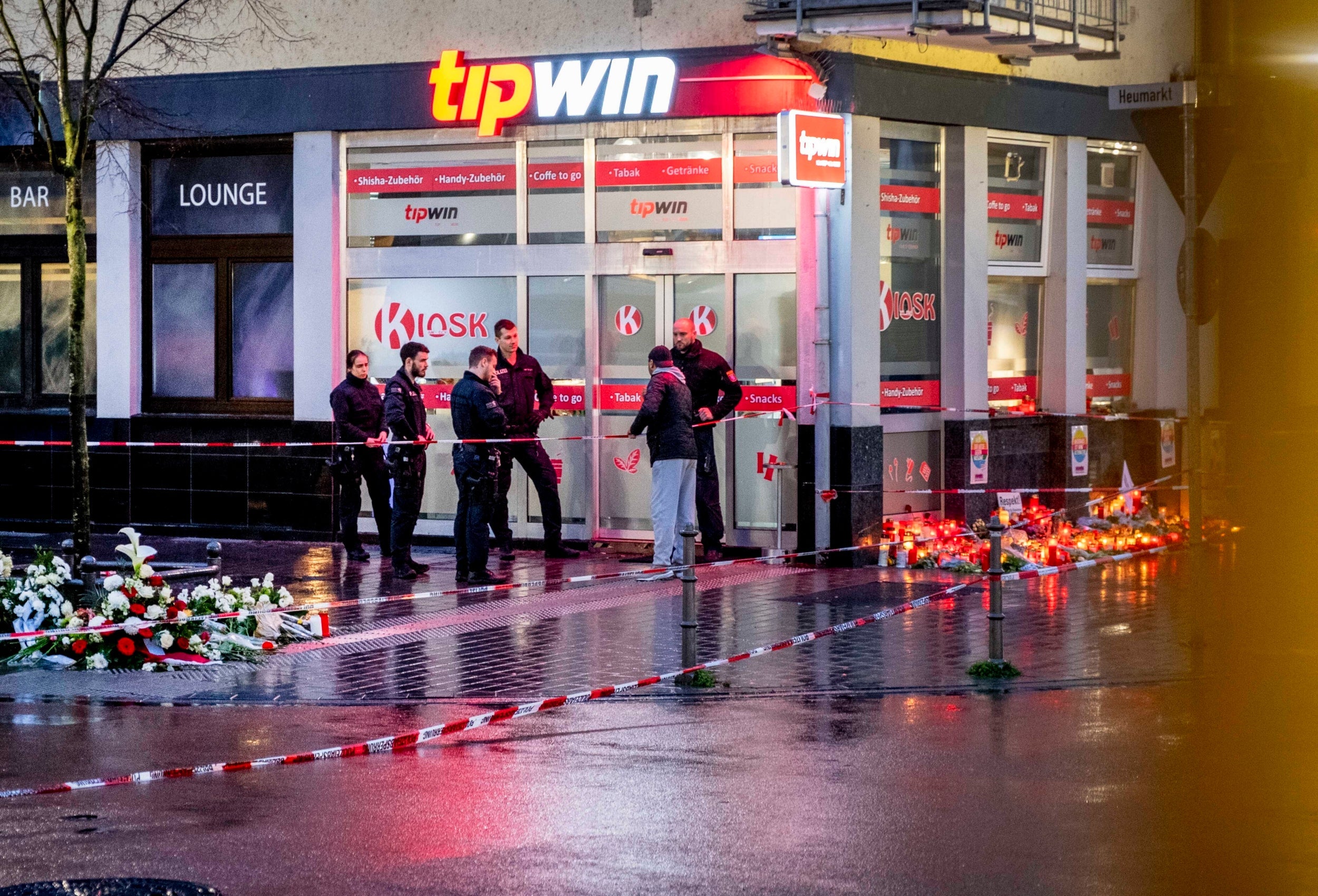 German police officers speak with a Muslim man at the scene of the Hanau attack