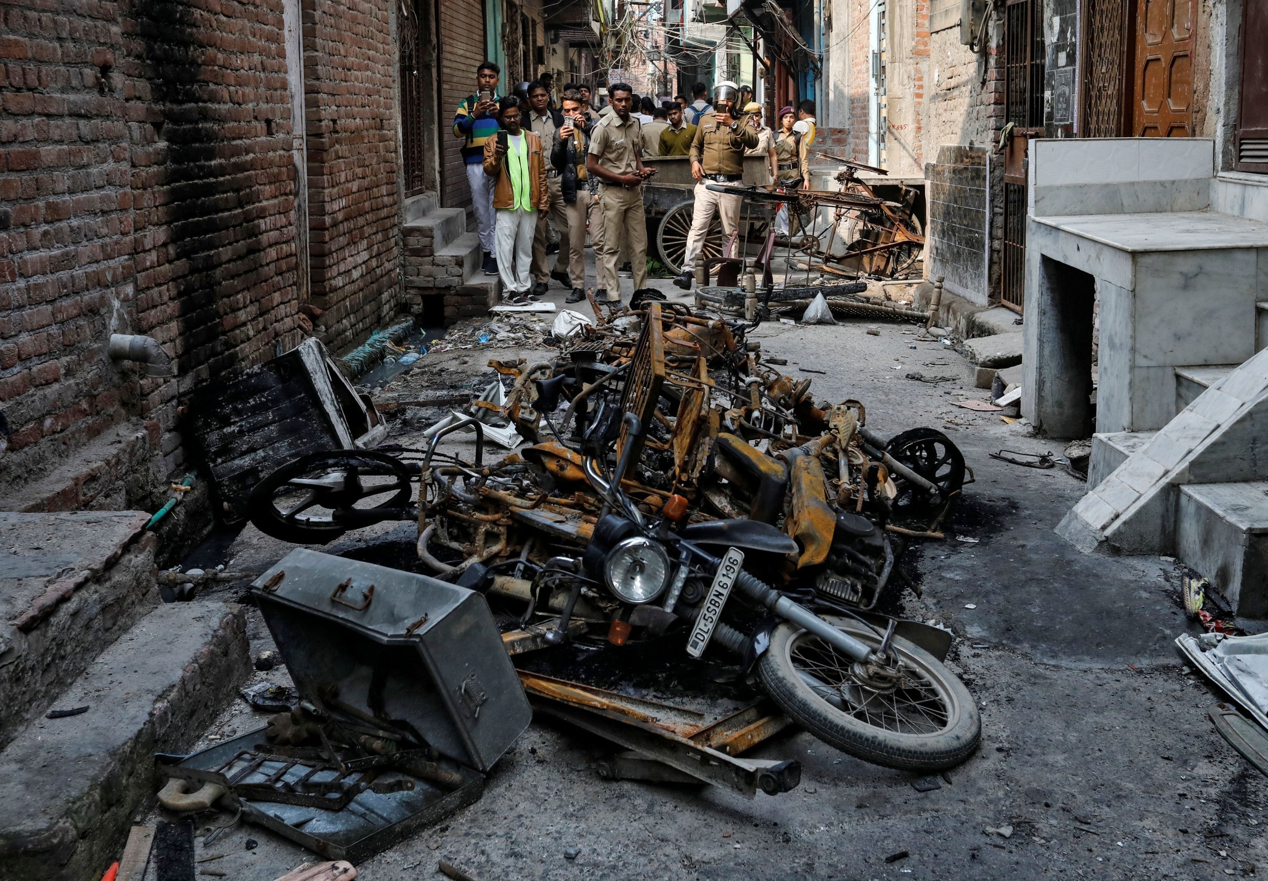 Police photograph burnt out properties owned by Muslims in a riot-affected area of northeast Delhi