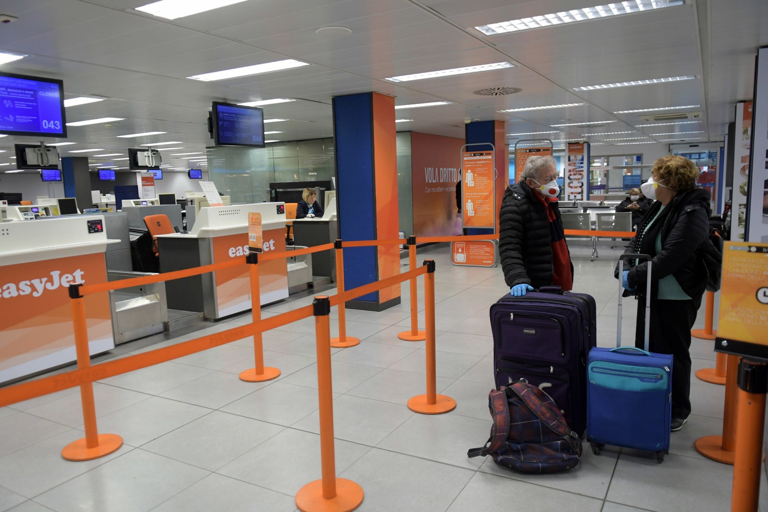 Passengers wear protective face masks inside the nearly deserted Linate airport in Milan