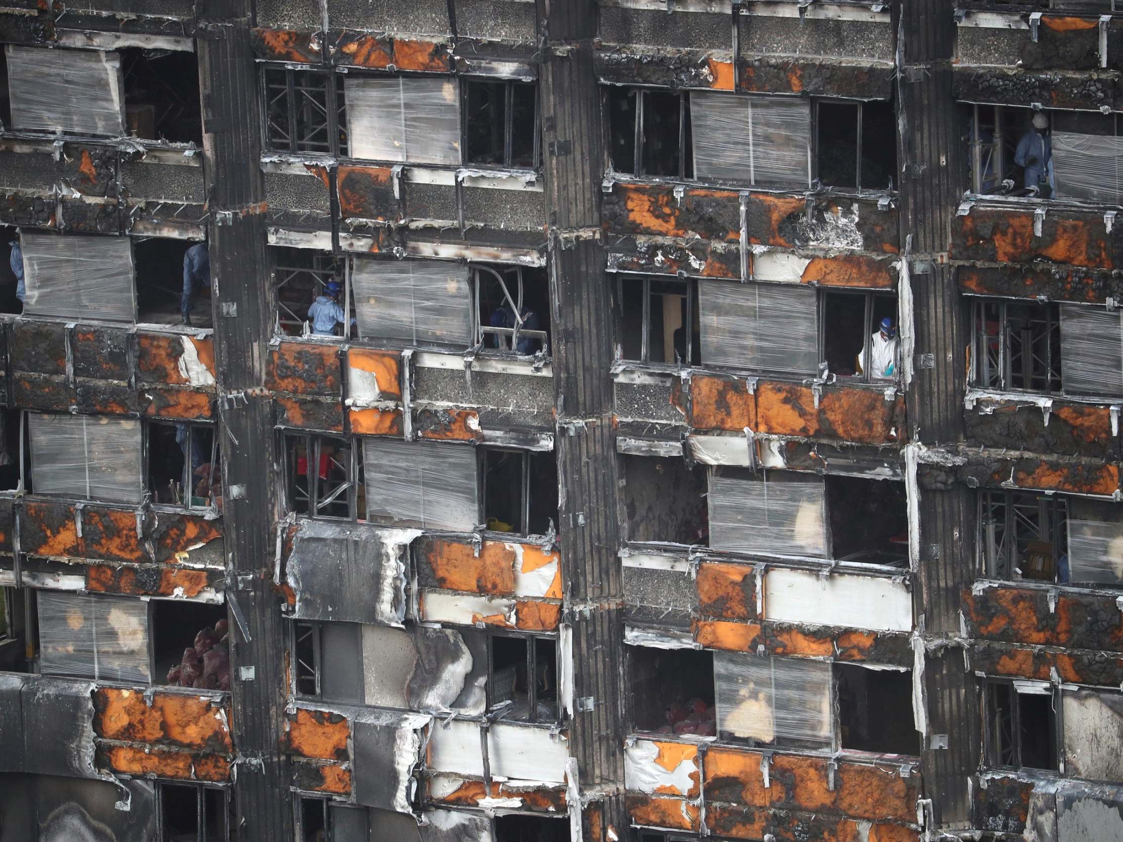 Workers stand inside the burnt out remains of the Grenfell Tower