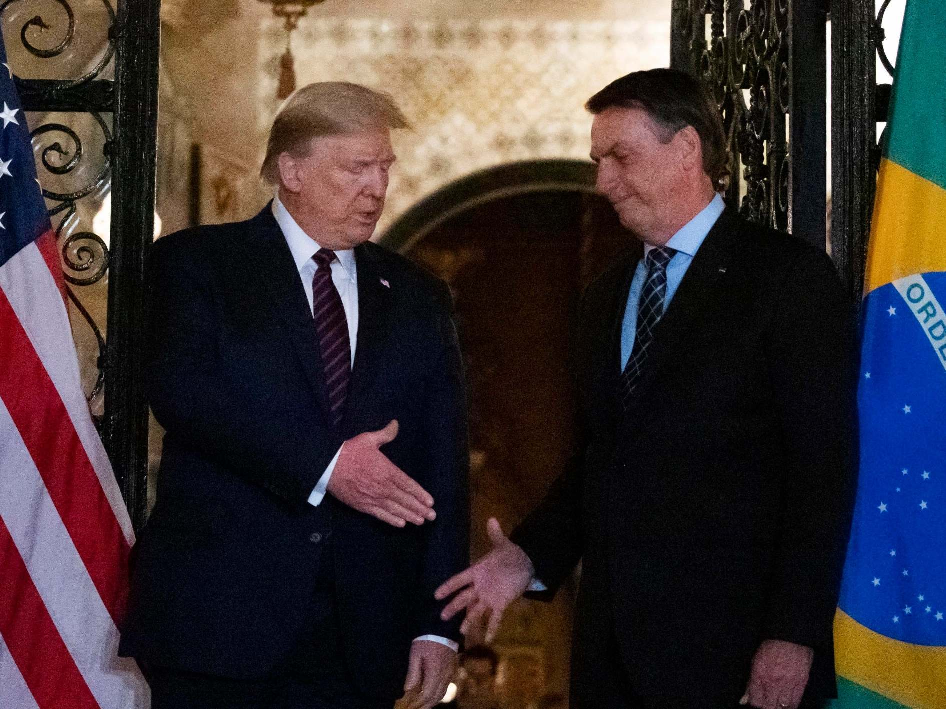 President Donald Trump shakes hands before a dinner with Brazilian President Jair Bolsonaro