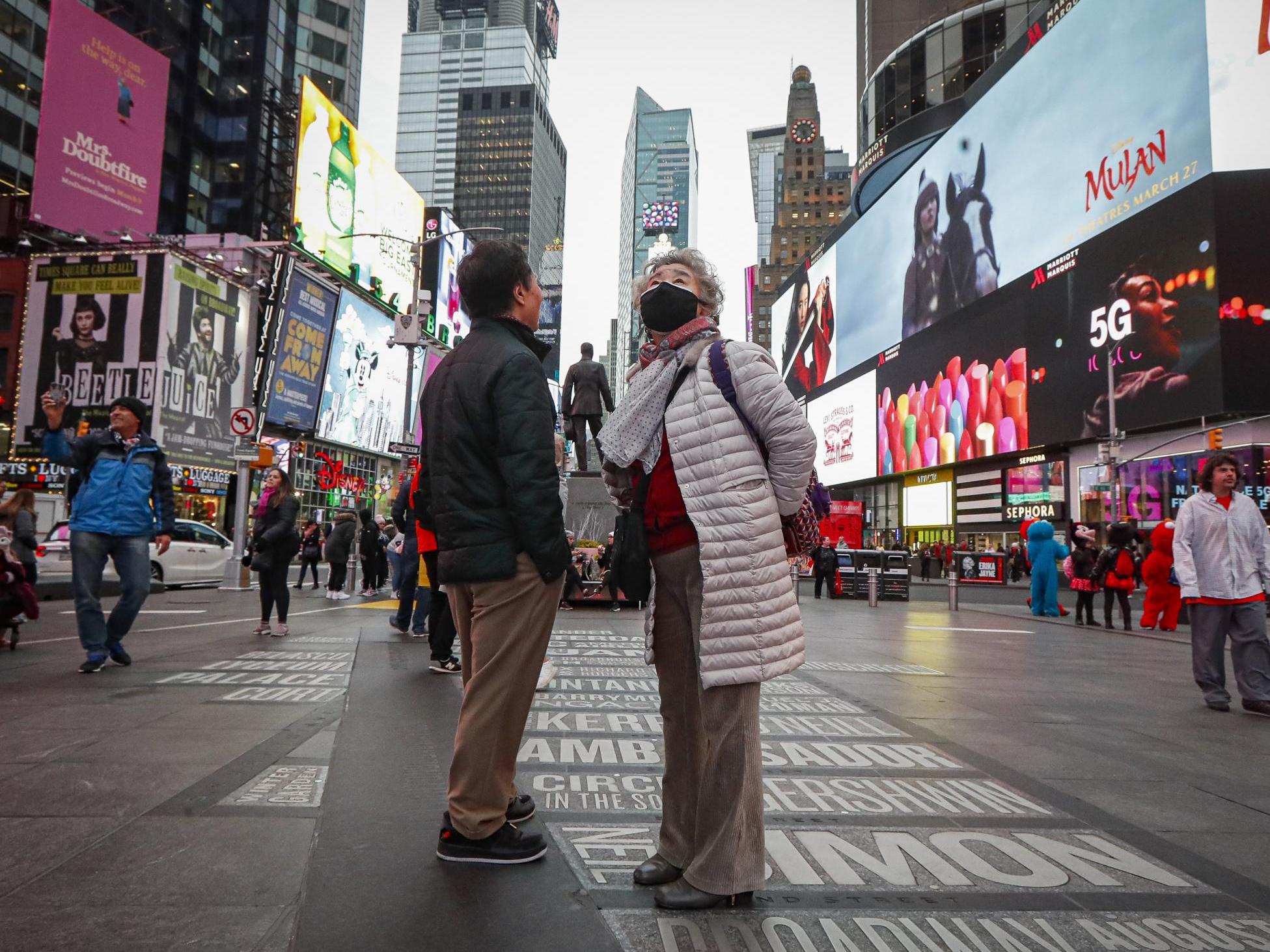 A pedestrian wearing a face mask stops in Times Square, Thursday, March 12, 2020, in New York.