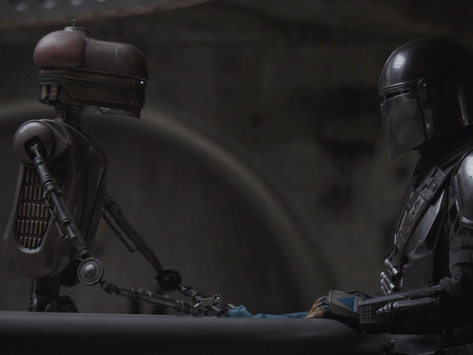 The Mandalorian converses with a droid behind the bar at the iconic Mos Eisley cantina