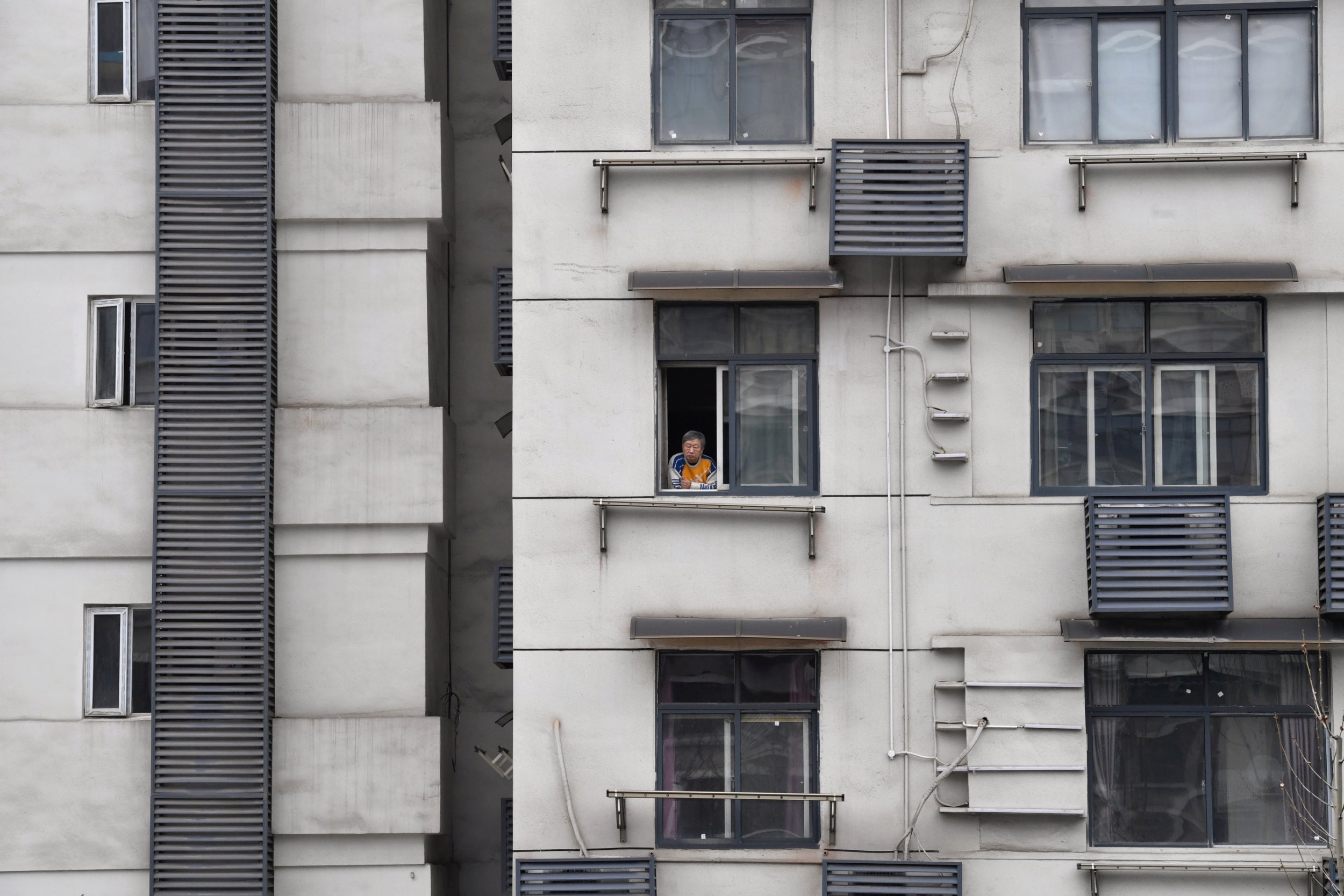 A Wuhan resident looks outside