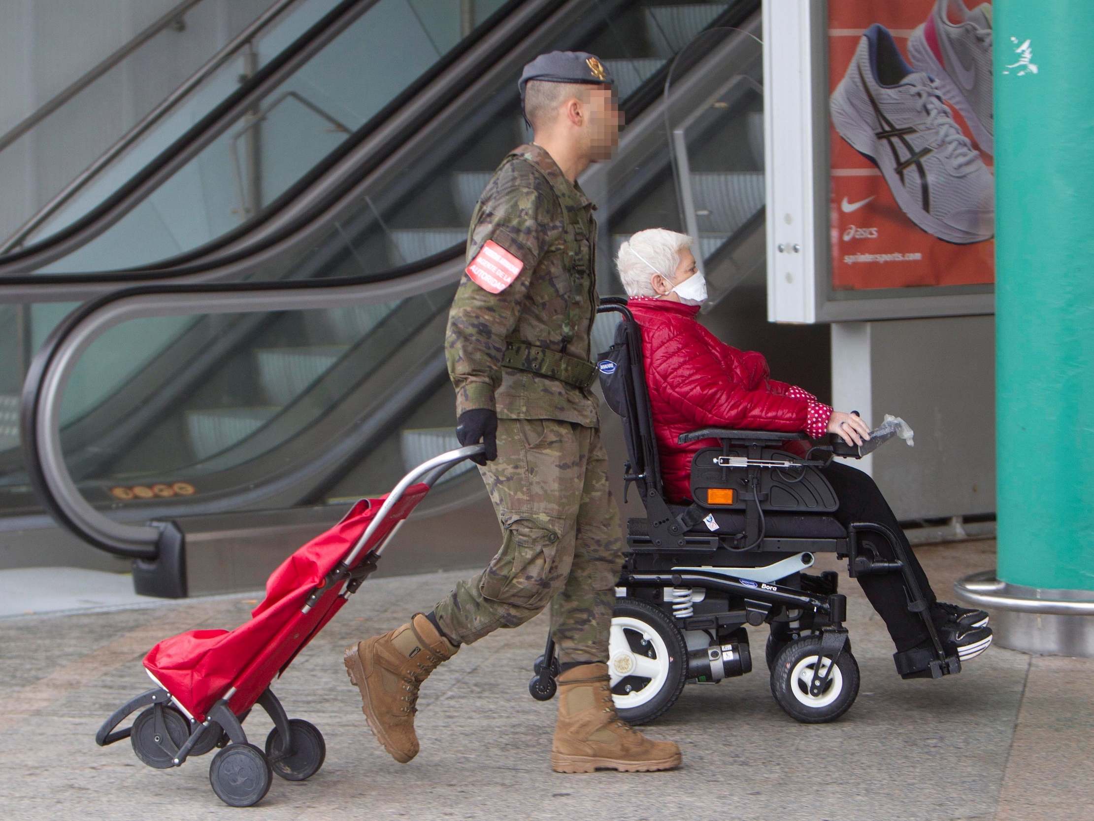 A Spanish soldier helps a disabled woman with her shopping at a supermarket in Vigo, northwestern Spain