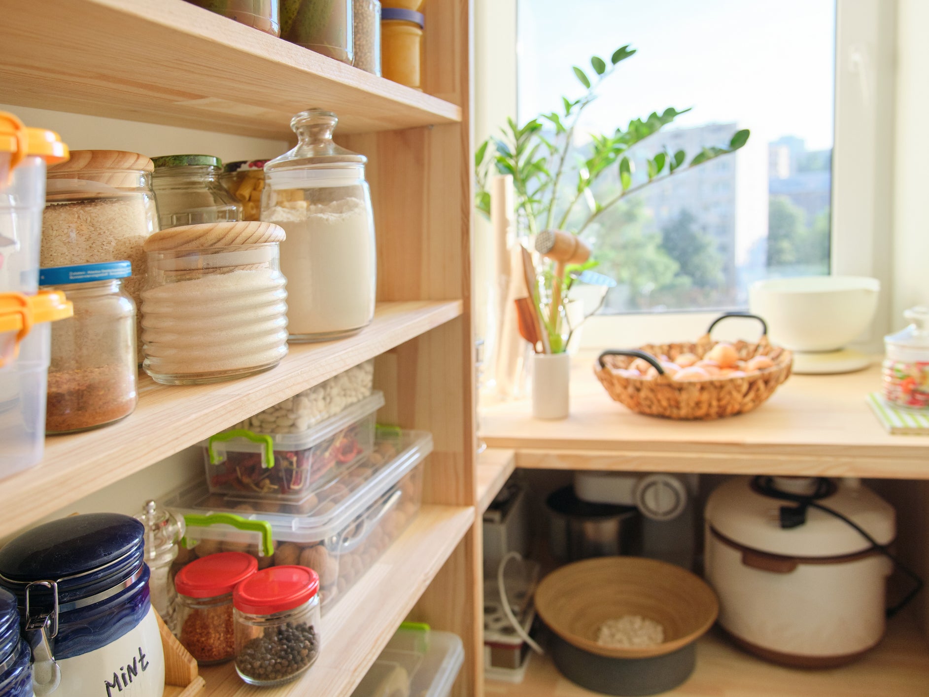 Wooden shelves with food and utensils, kitchen appliances in the pantry.