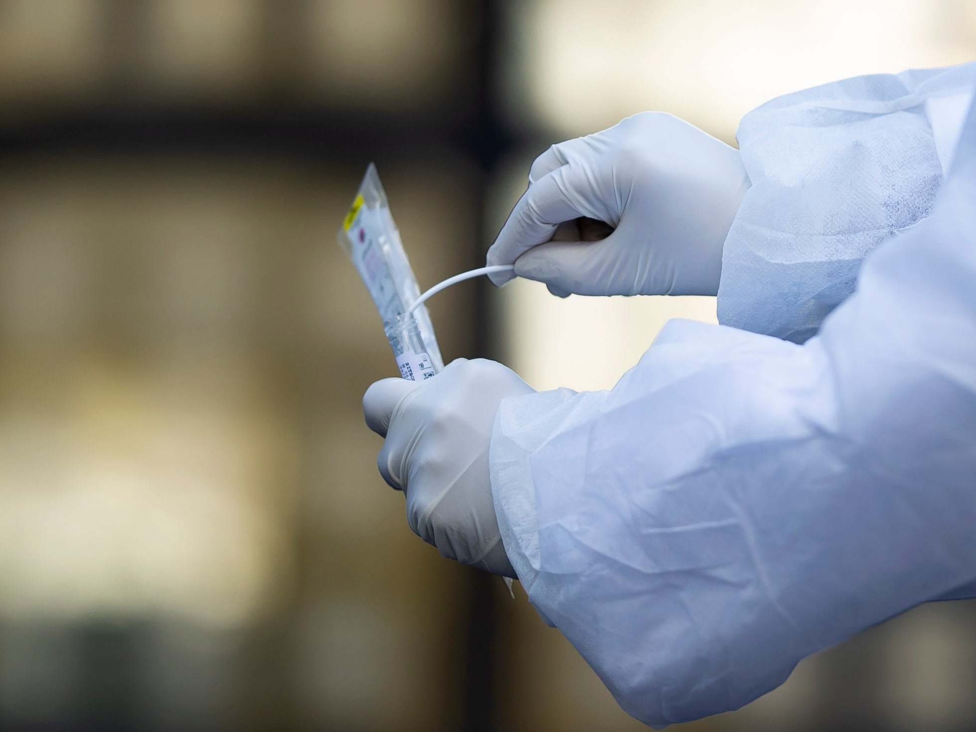 A medical biologist handles a swab to test a patient for the SARS-CoV-2 coronavirus causing the Covid-19 disease, at a drive-through facility