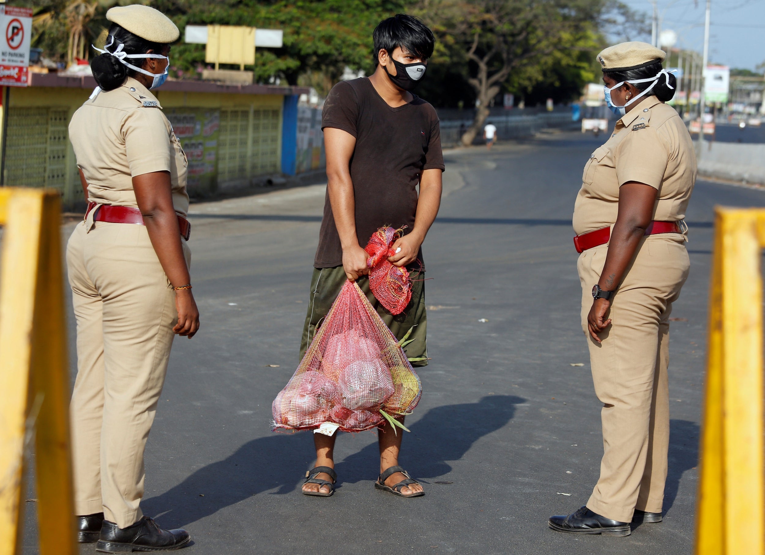 A man carrying home vegetables is stopped by police at a barricade on a road on Wednesday in Chennai, India