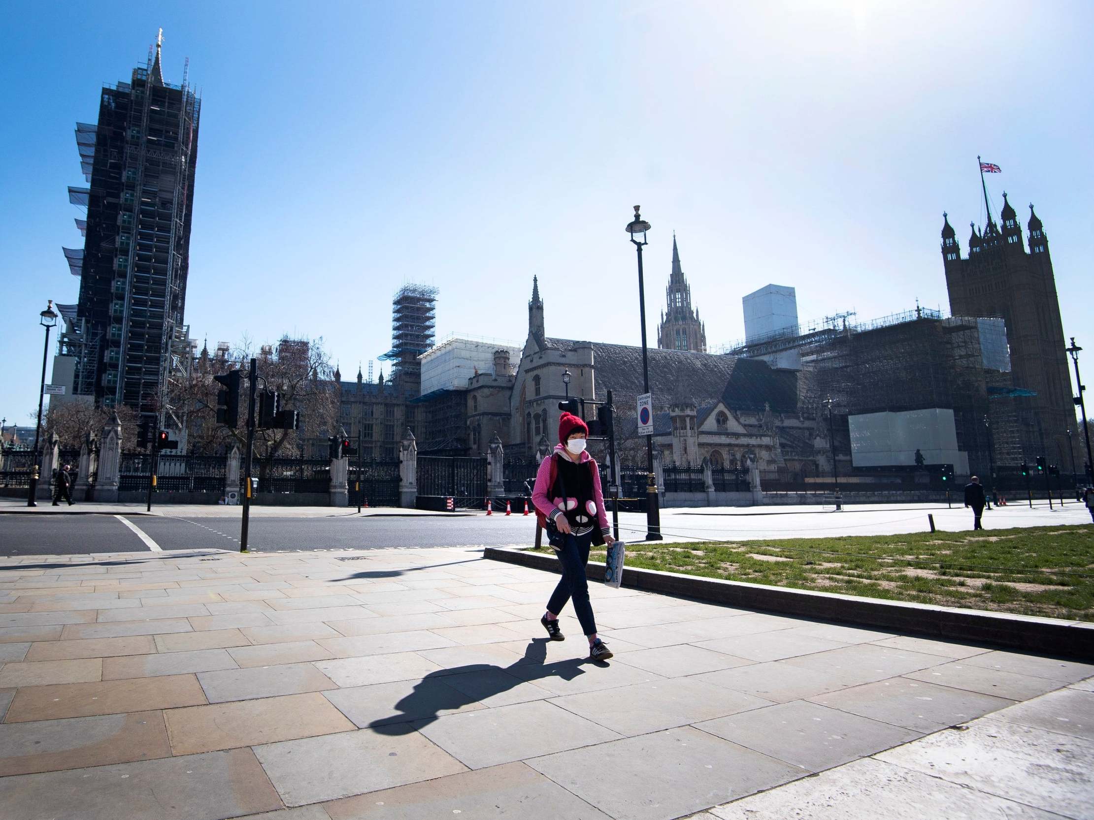 A pedestrian wearing a protective mask walks in Parliament Square after parliament shut down for a month