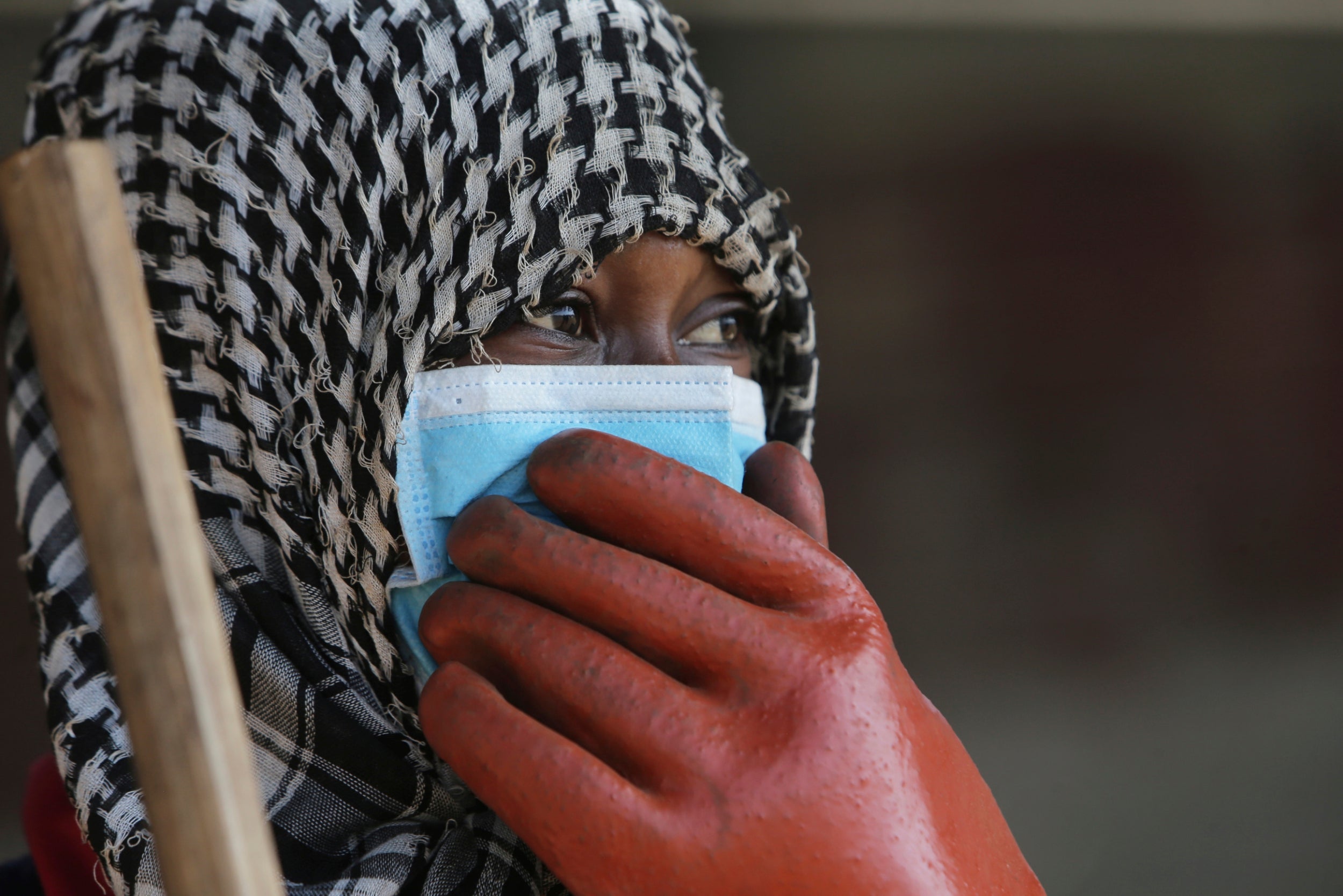 A council worker wears a face mask while cleaning the streets in Harare, Zimbabwe on Wednesday