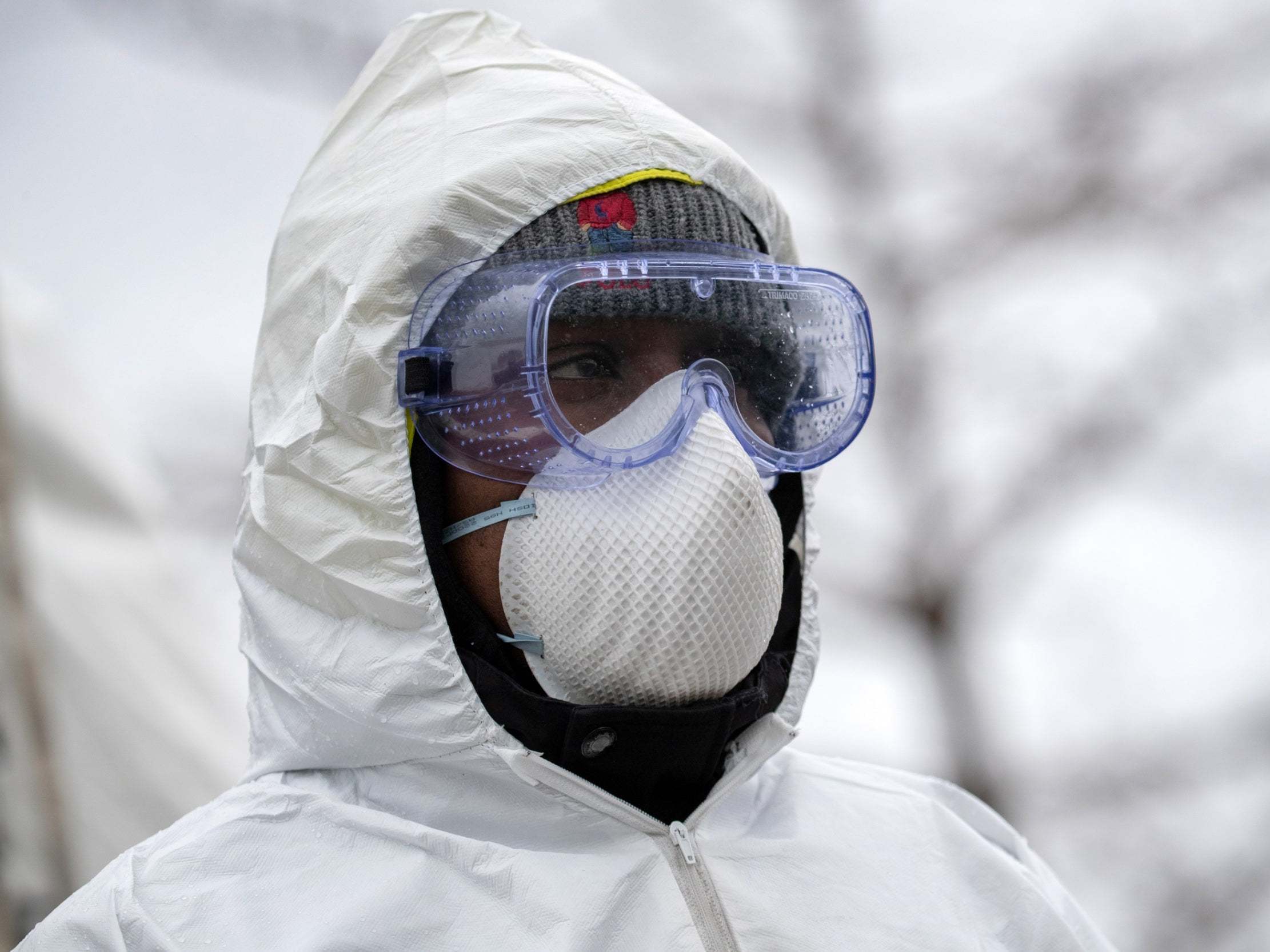 A health worker dressed in personal protective equipment (PPE) awaits new patients at a drive-thru coronavirus testing station