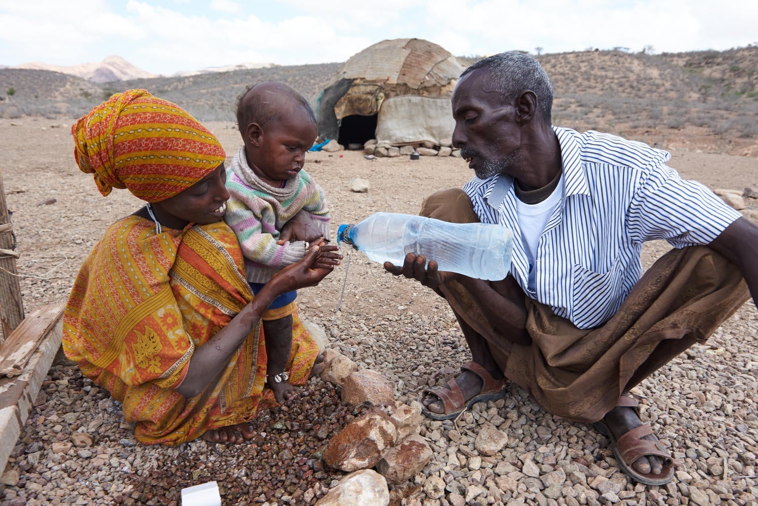 Using a Unicef-supported water point, a woman and her husband wash their child outside their home in the village of Abdoya in Djibouti. Abdoya is in a remote zone, with a desert-like climate, and is home to hundreds of families who live with only a few natural resources