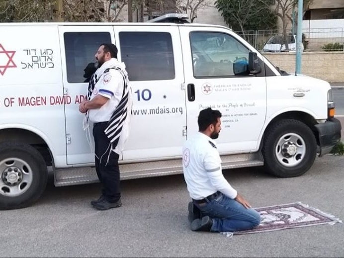 The two paramedics pray facing their respective holy places