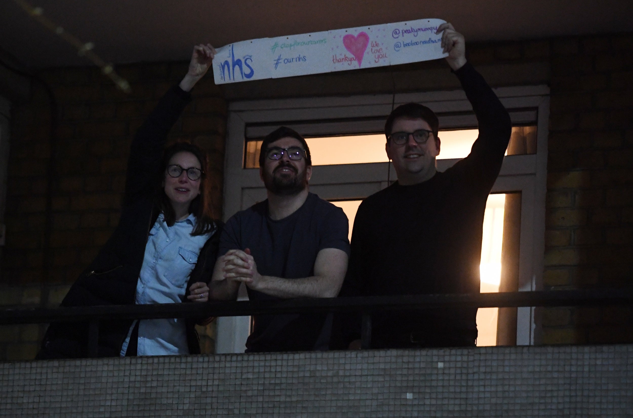 People clap from a block of flats opposite St Thomas' Hospital in London. Briton's were encouraged to clap for carers at 8pm local time to celebrate employees of the NHS