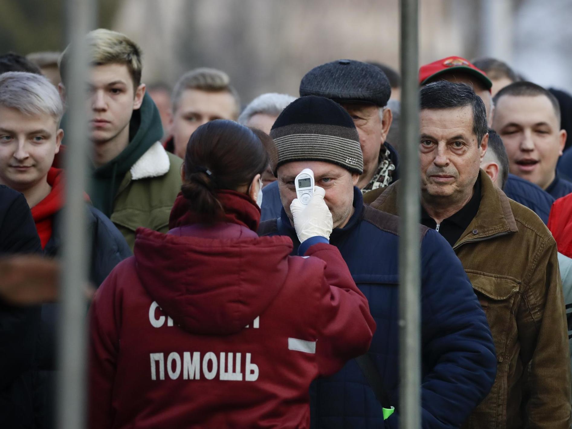 A medical worker checks the temperatures of footballl fans as they enter a stadium during the Belarus Championship match on Saturday